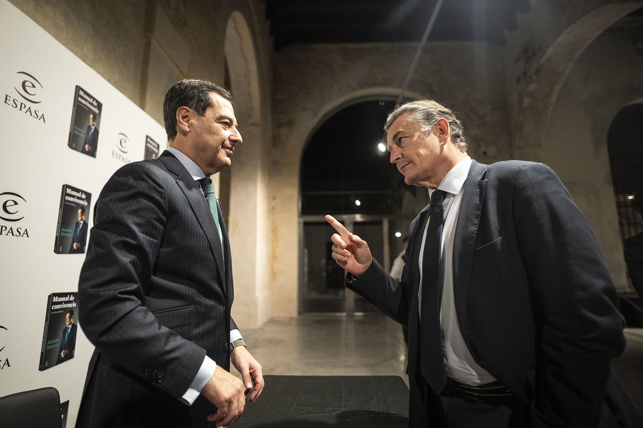 El consejero de Sanidad, Antonio Sanz, habla con el presidente Juanma Moreno durante una presentación de su libro. - 