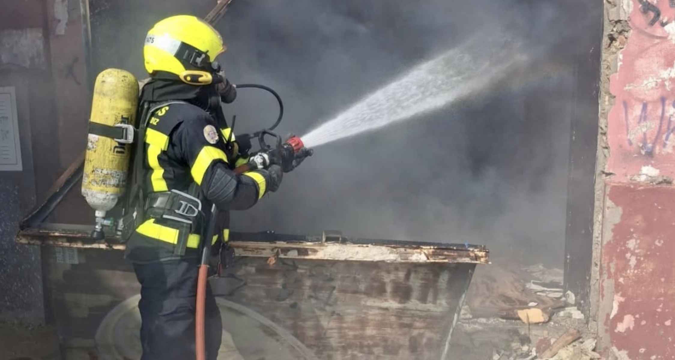 Un bombero, tratando de apagar el fuego en un local abandonado de la calle Muro