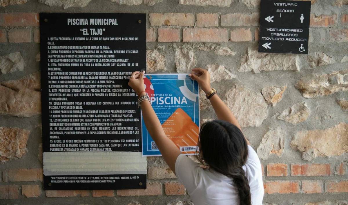 Una joven coloca el cartel de abierto en la piscina de El Tajo de Grazalema