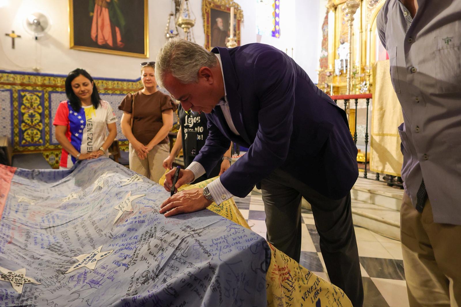 Sanz firmando en la bandera de Venzuela en la capilla de Santa Marina. 