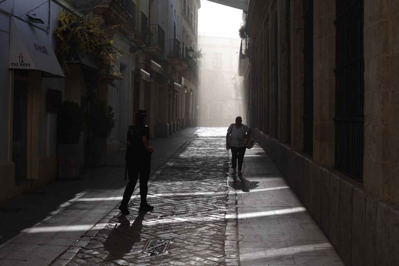Una mujer camina por la calle Latorre, junto a un Policía Local, con la humareda al fondo.