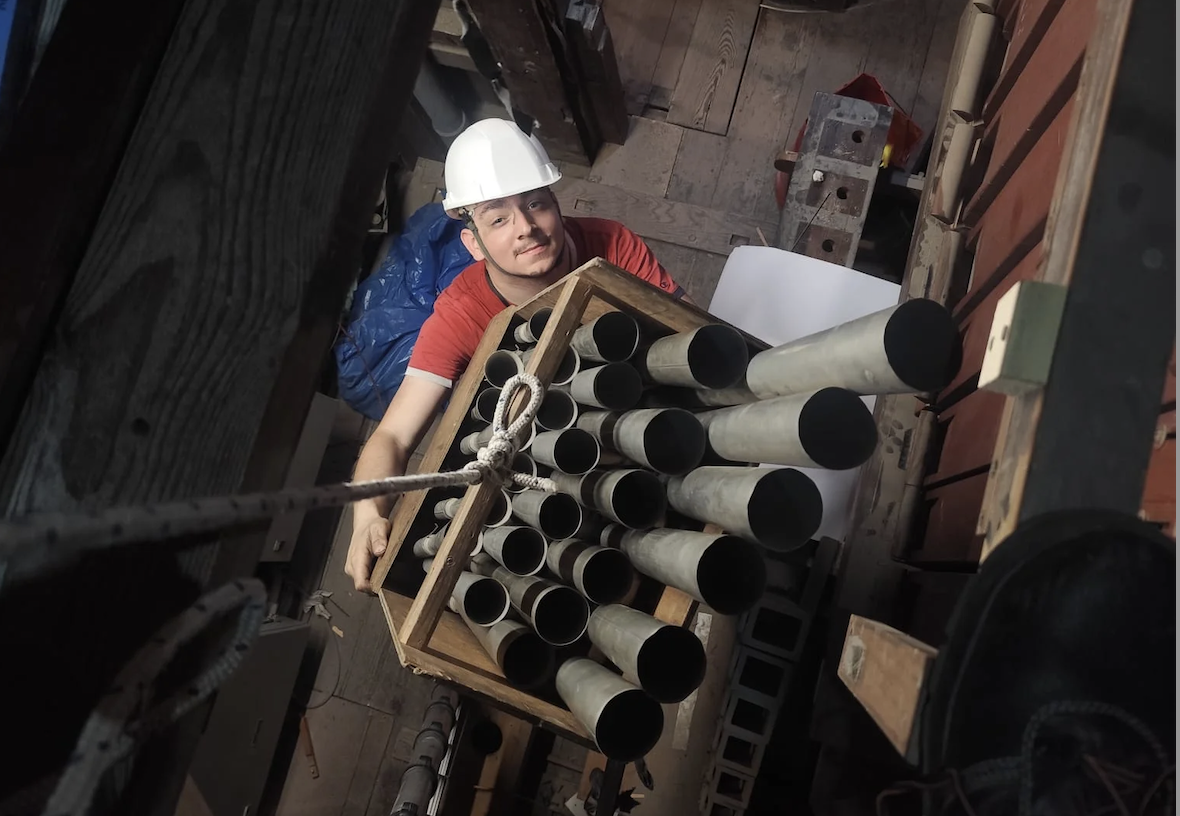 Un operario con tubos del órgano durante su restauración. 