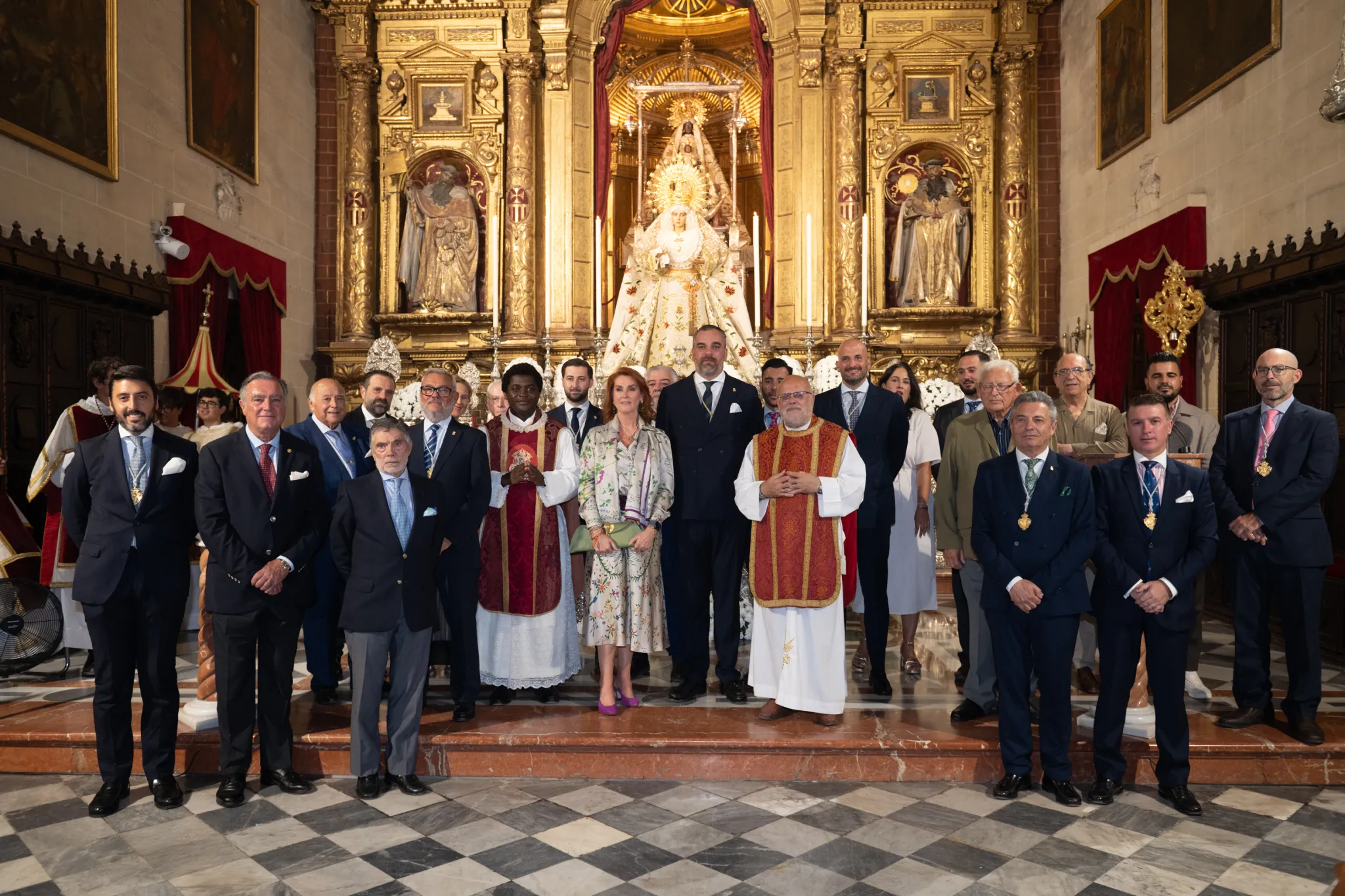 María Luisa Cuñado con los sacerdotes, hermano mayor y junta de gobierno de la hermandad ante la Virgen situada en el altar mayor de lq Merced. 