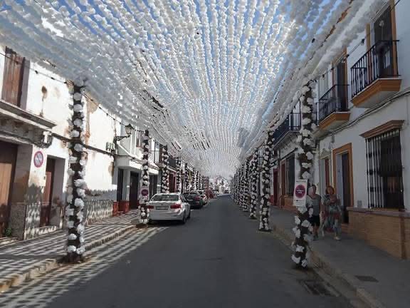 Calle principal de Almonte cubierta de flores. 
