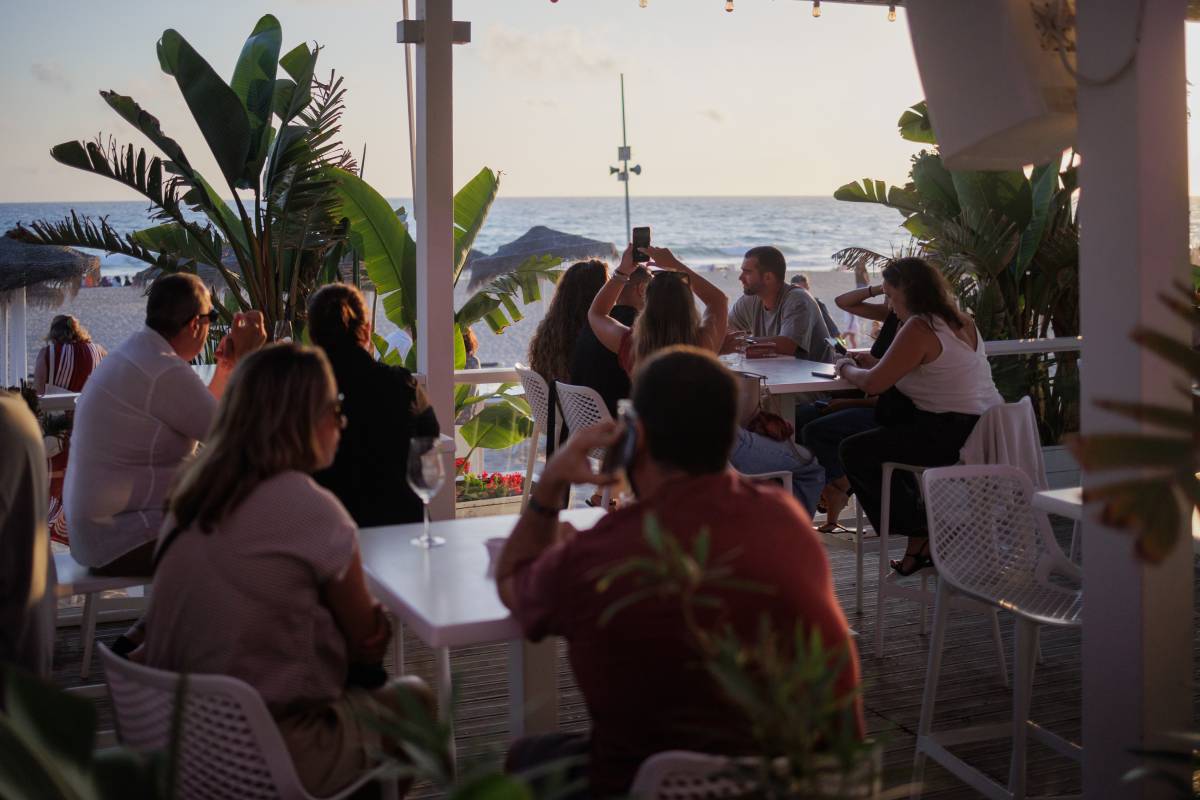 Clientes del chiringuito Santorini Beach, disfrutando del atardecer de Sancti Petri.