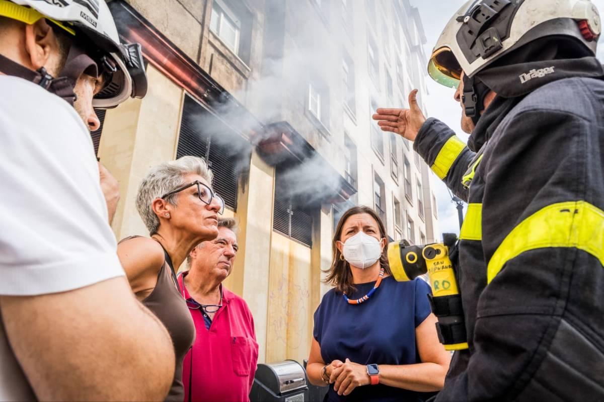 Un bombero explicando la situación a los vecinos. - Un bombero explicando la situación a los vecinos.