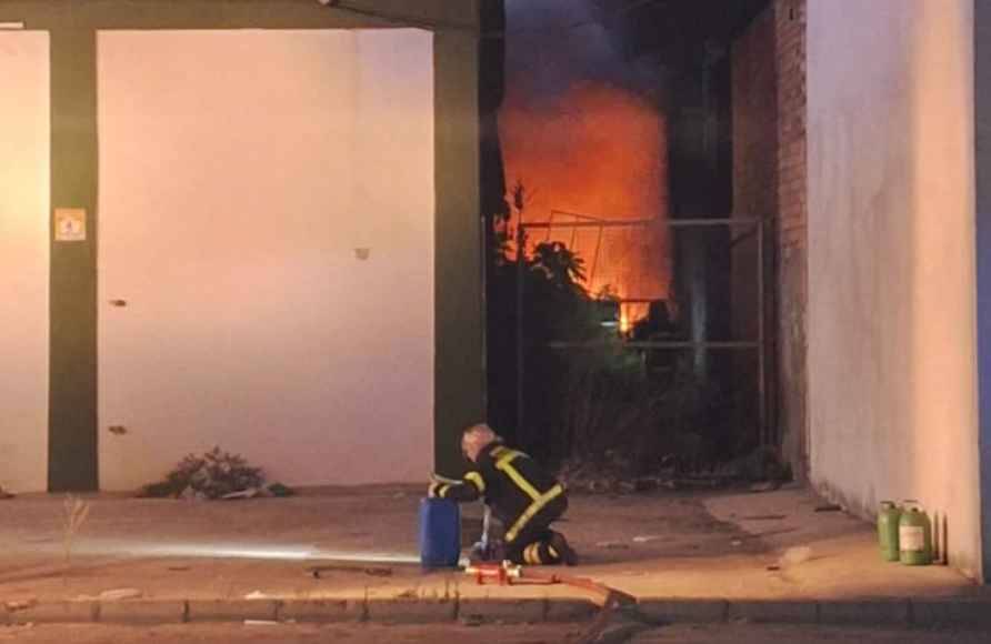 Un bombero, con el fuego de la nave en El Puerto de fondo. - Un bombero, con el fuego de la nave en El Puerto de fondo.