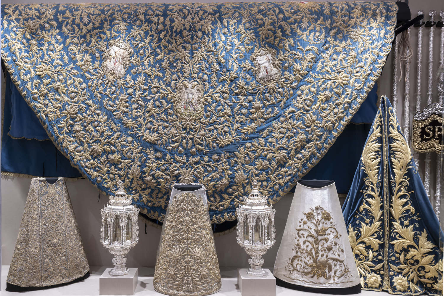 La vitrina que contiene el magnifico manto de la Virgen junto asadas y piezas de orfebrería. 