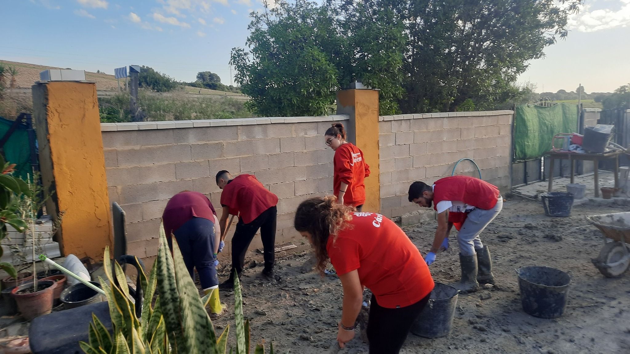 Unos jóvenes ayudan a una vecina afectada por las inundaciones de la DANA. - 