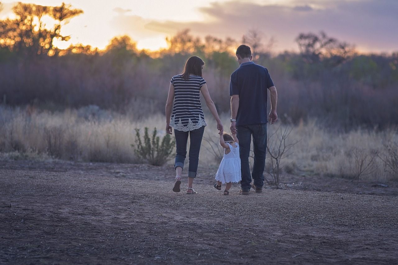Una familia, con su papá y su mamá, pasean con una niña pequeña. - 