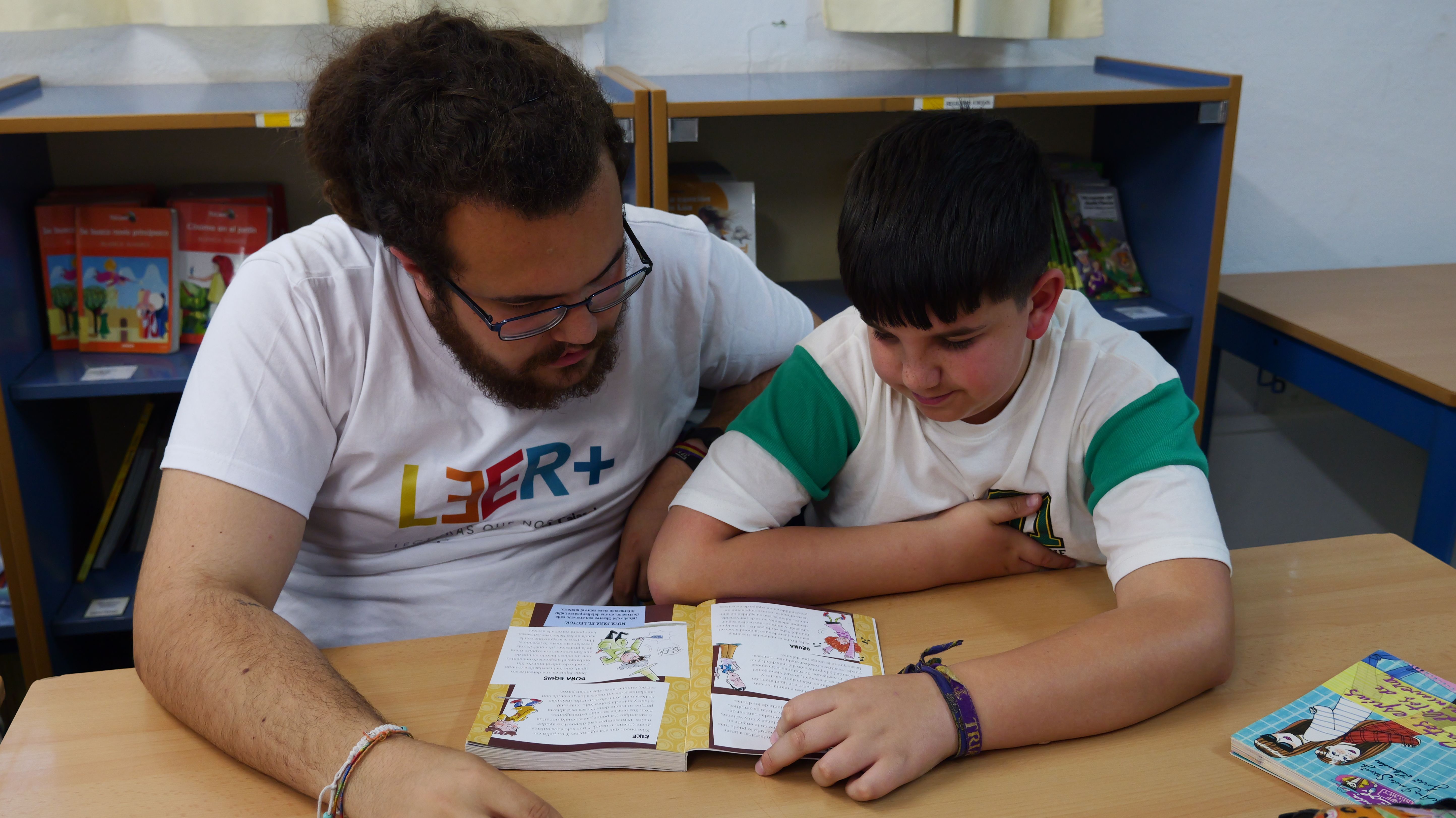 Un voluntario enseña a leer a un alumno en un colegio de Andalucía.   - 