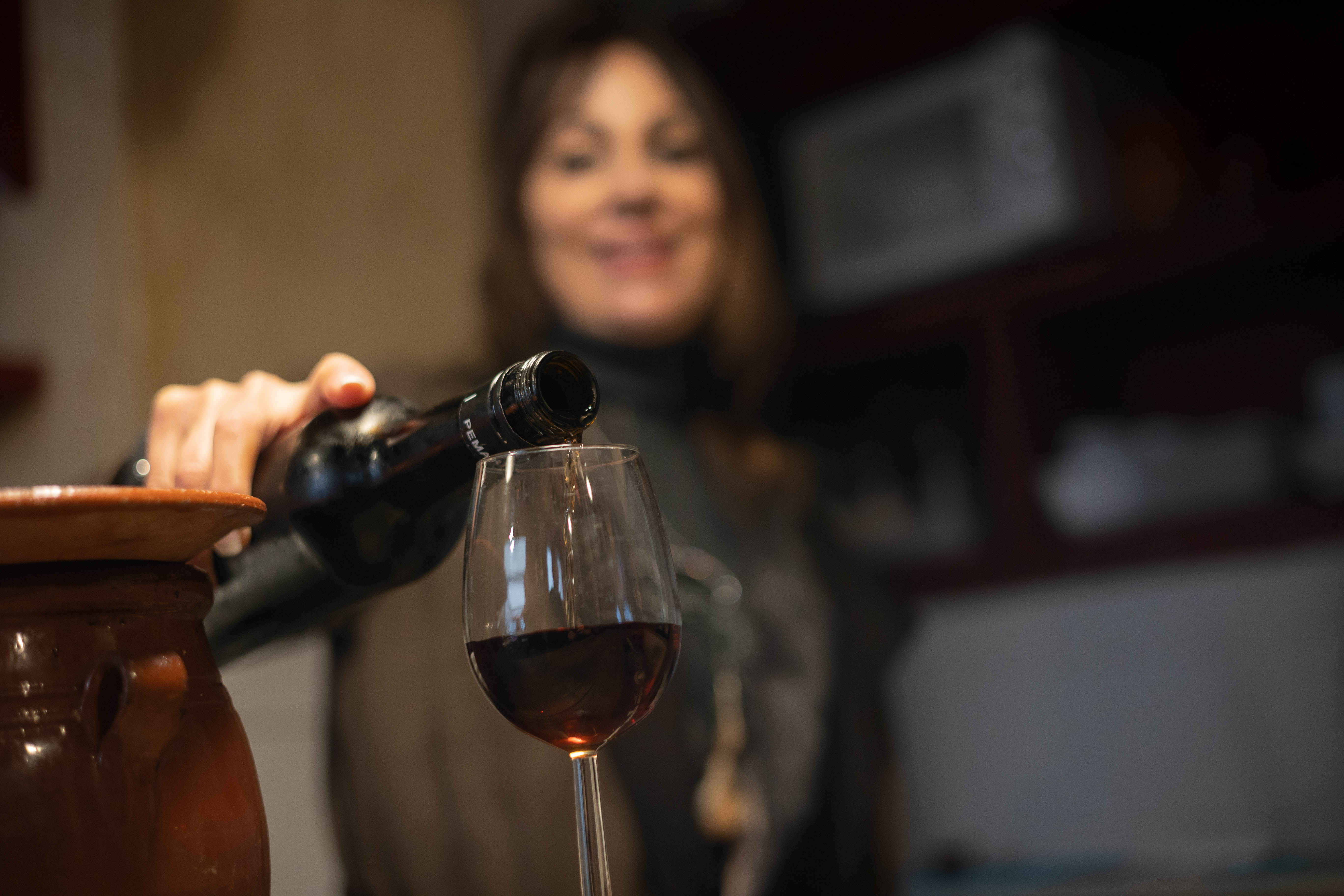 Blanca sirve una copa de vino desde la barra.