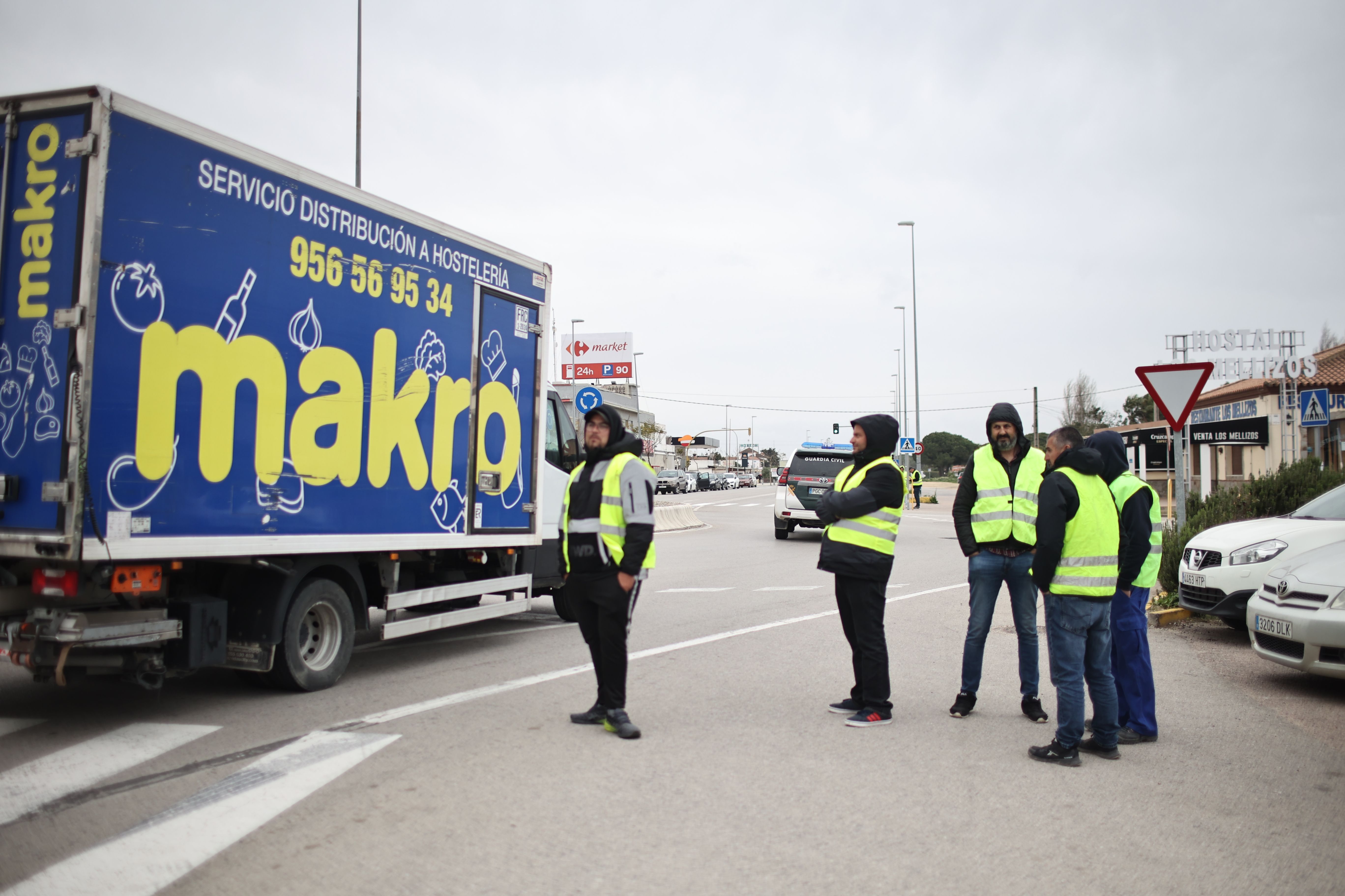 Uno de los piquetes apostados en una de las rotondas de El Colorado, en Conil, este lunes, al paso de un camión, escoltado por la Guardia Civil, de una empresa que da servicio a hostelería.