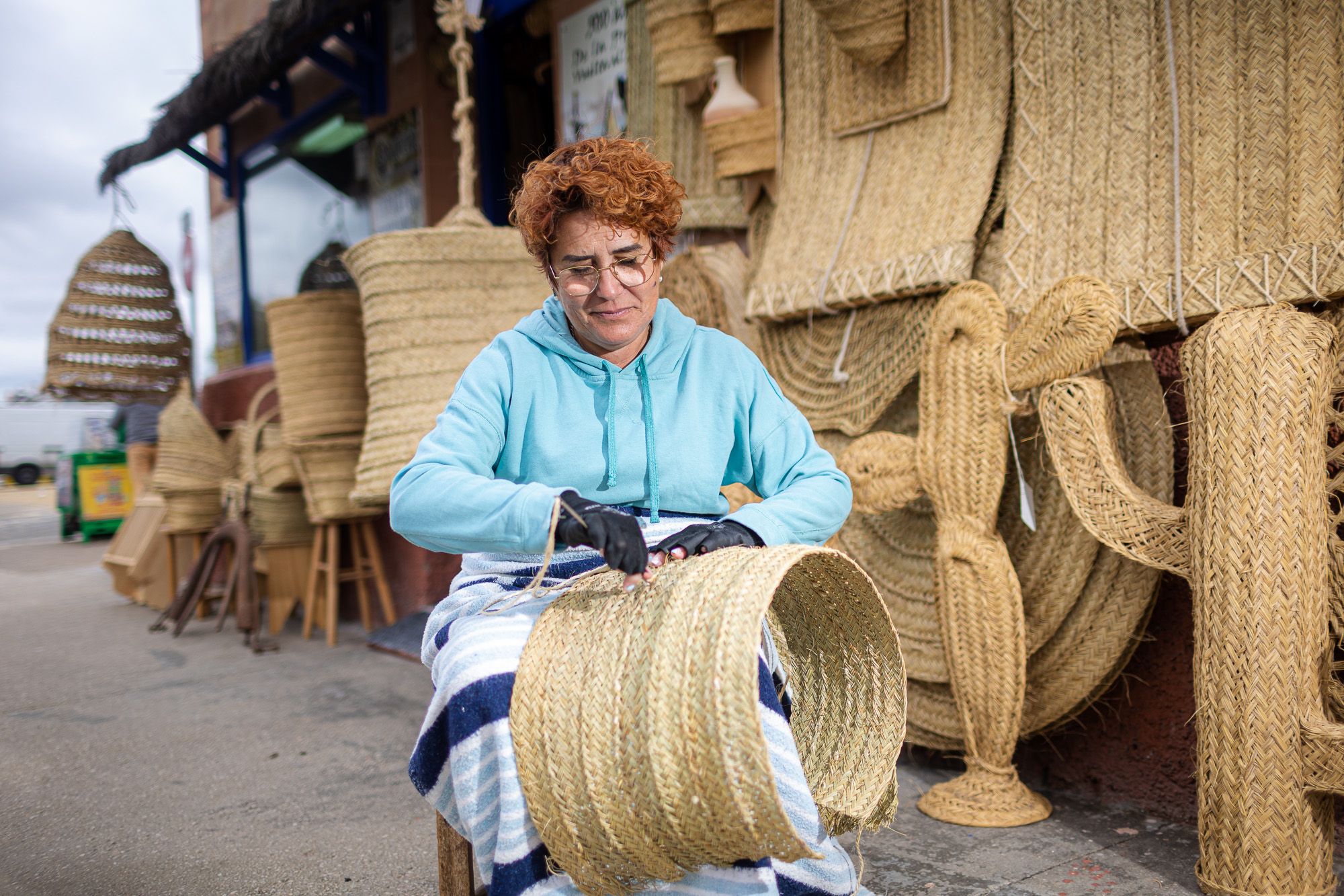 Caridad Sumariva, de Sanlúcar, una de las pocas esparteras de Andalucía, cosiendo una persiana frente a su tienda. Caridad Sumariva, de Sanlúcar, una de las pocas esparteras de Andalucía, cosiendo una persiana frente a su tienda.