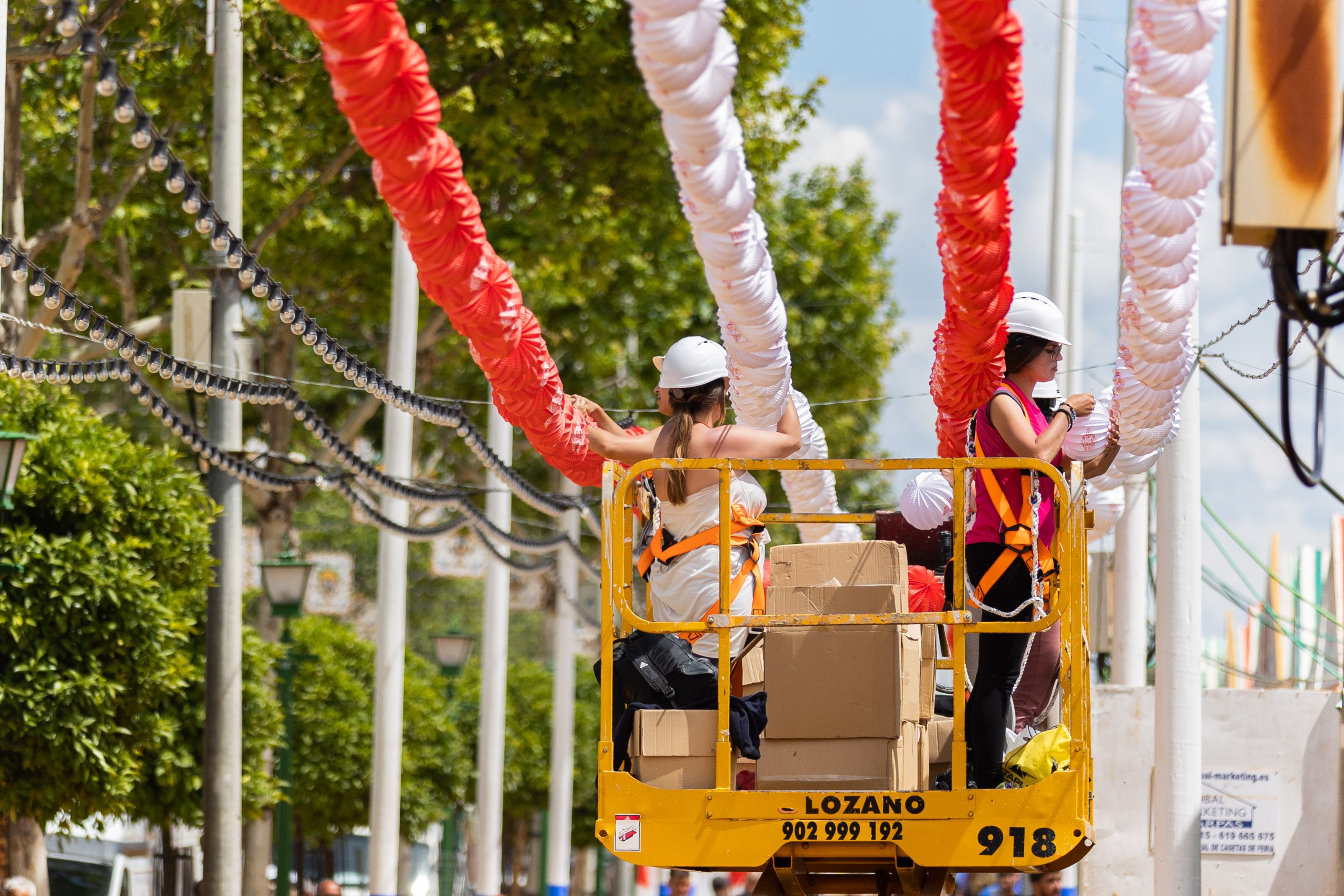 Dos operarias finalizando el cielo de farolillos, en el real de Los Remedios de la Feria de Abril de Sevilla.