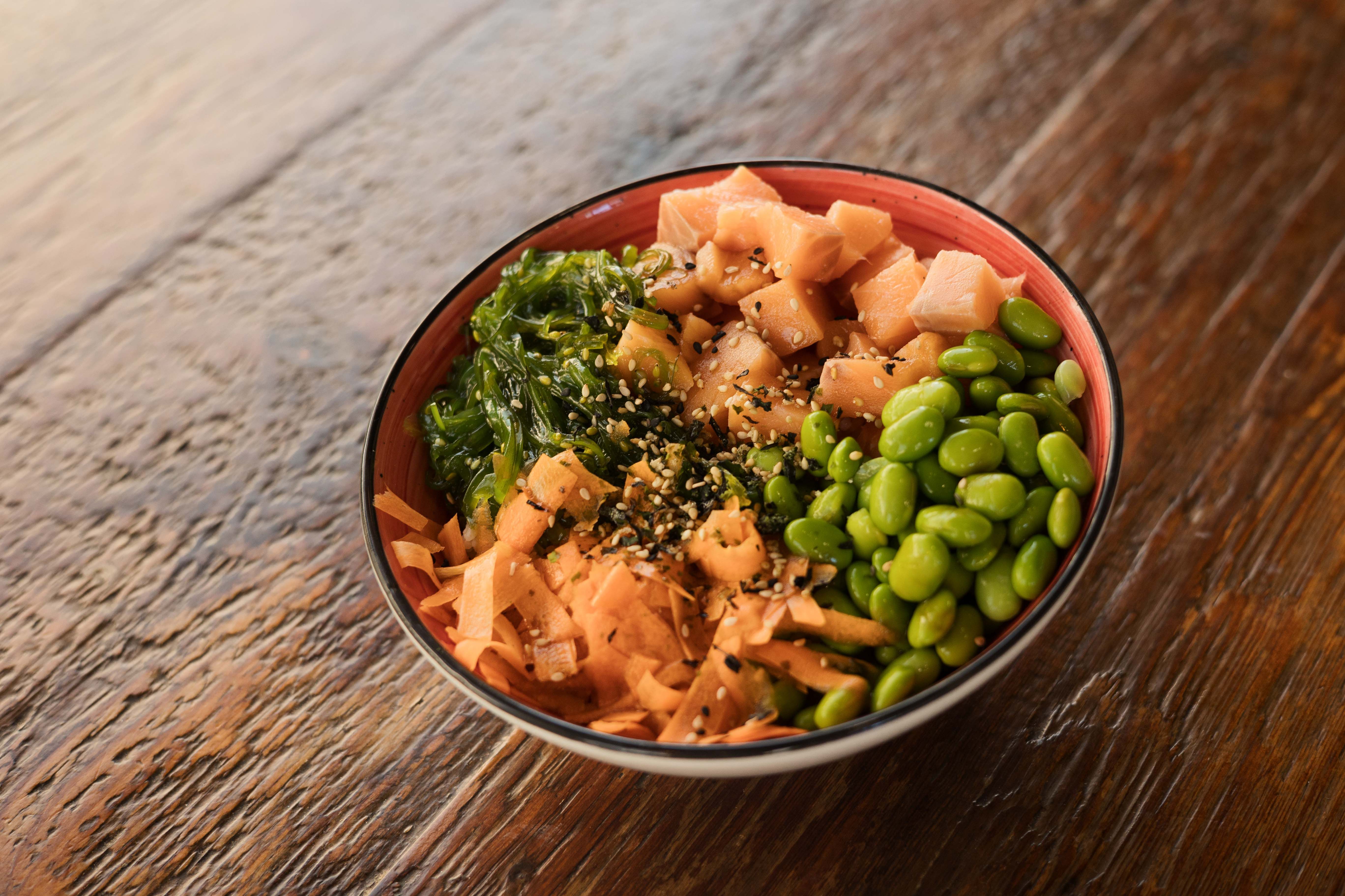 Poke de salmón con arroz japonés, salsa de soja casera, edamame, wakame, zanahoria, algas hawaianas y sésamo.