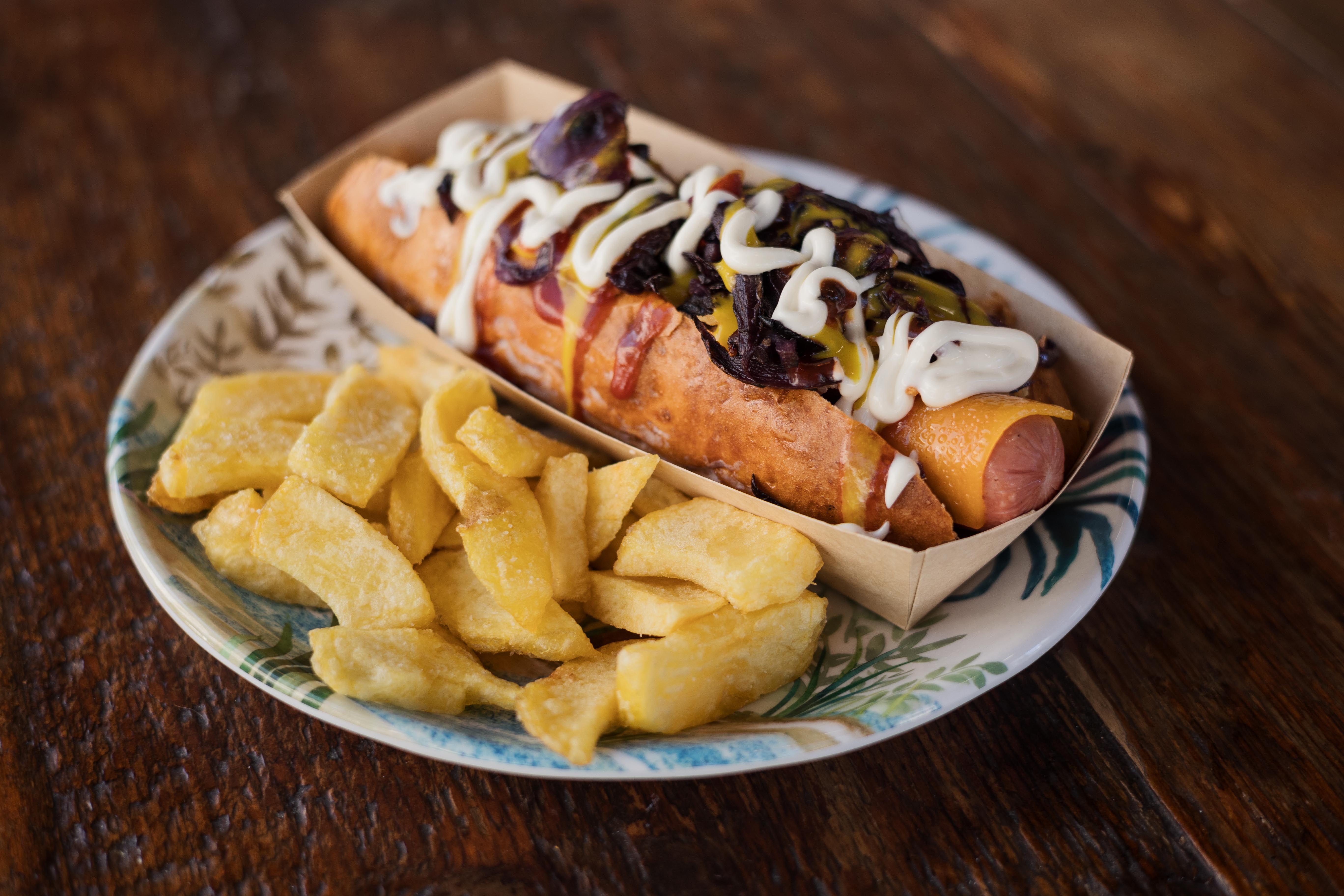 Perrito caliente con verdura, bacon, queso, cebolla frita y tres salsas.