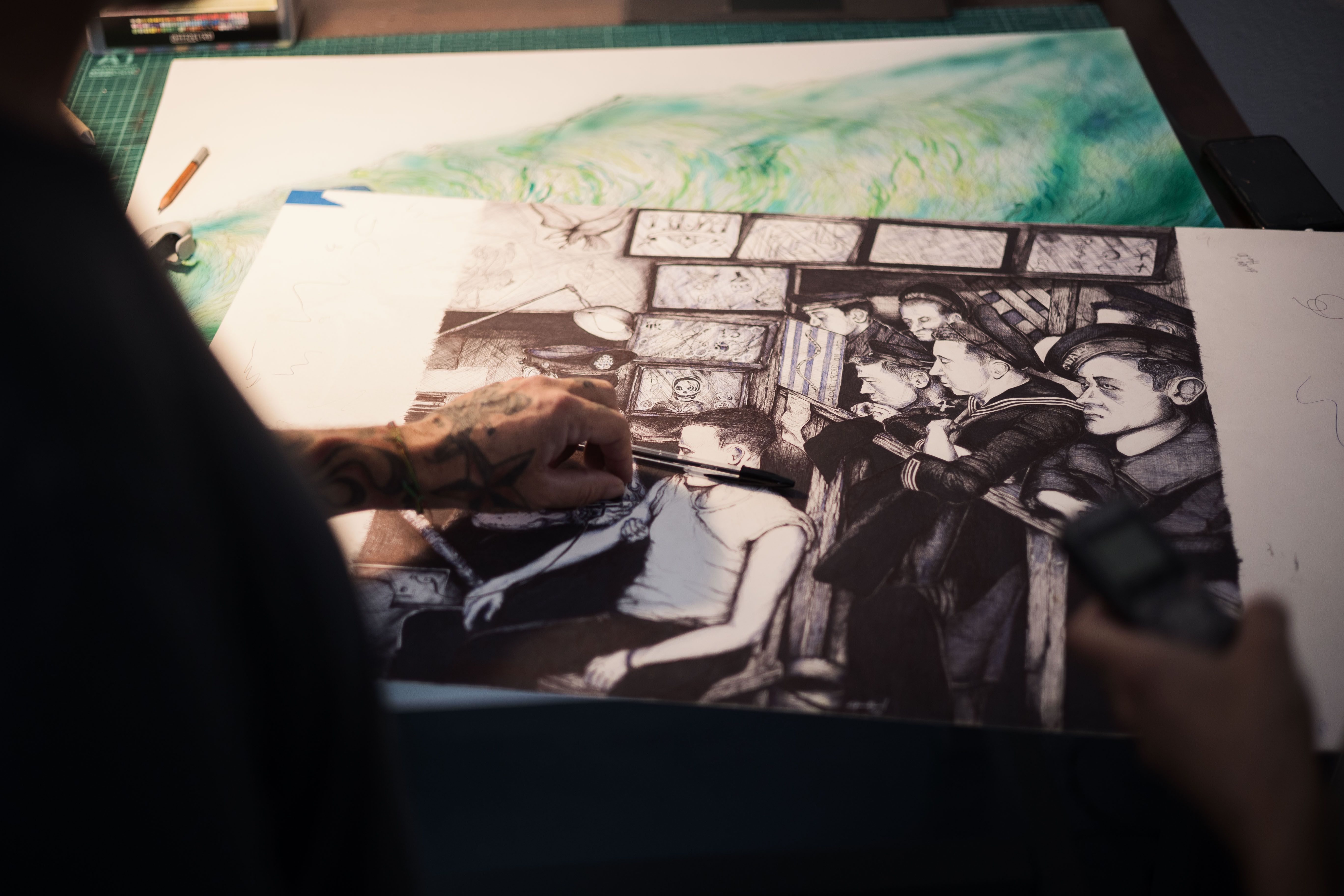 El artista muestra un dibujo hecho con un bolígrafo azul y otro negro.