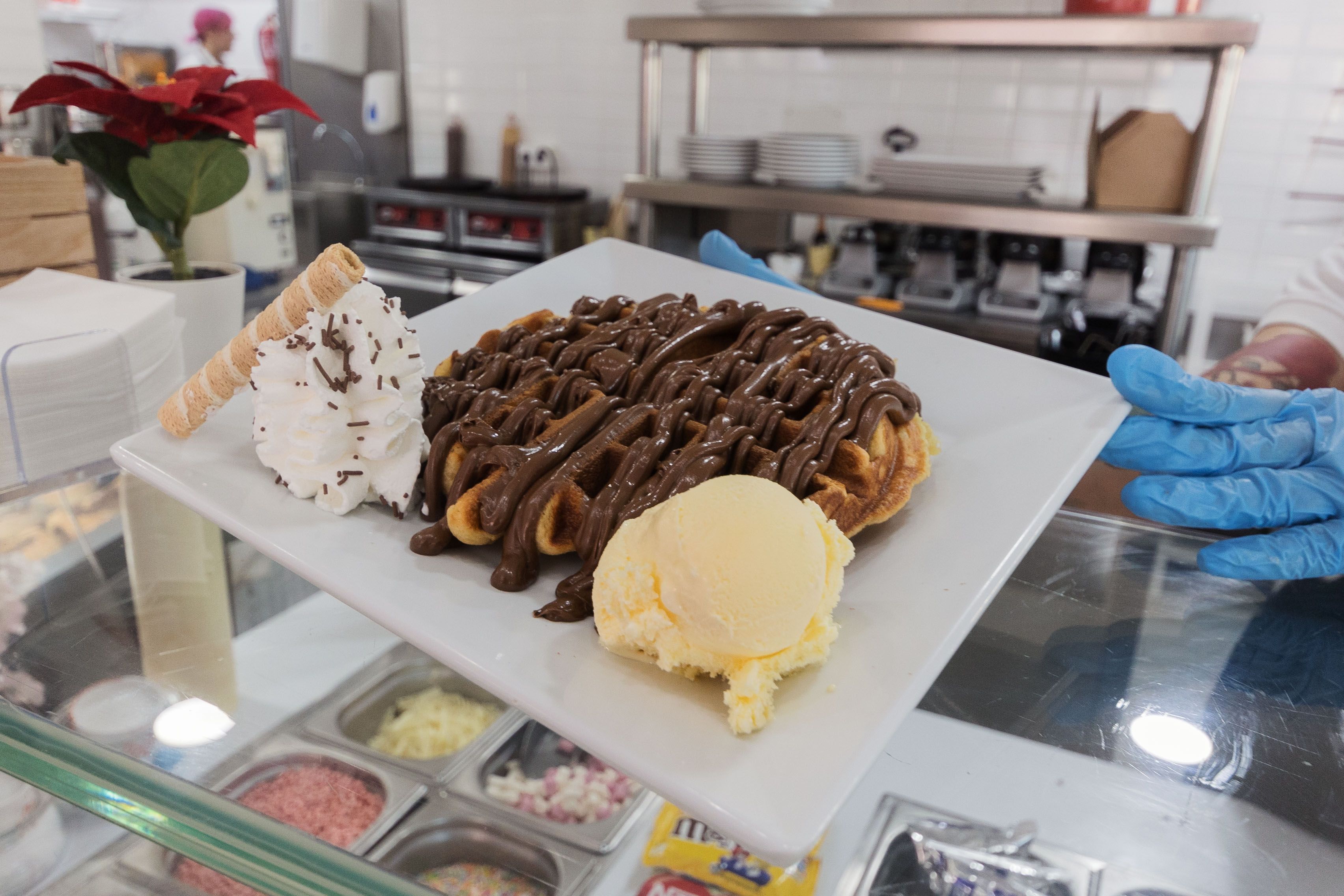 Un gofre con sirope, nata y helado.