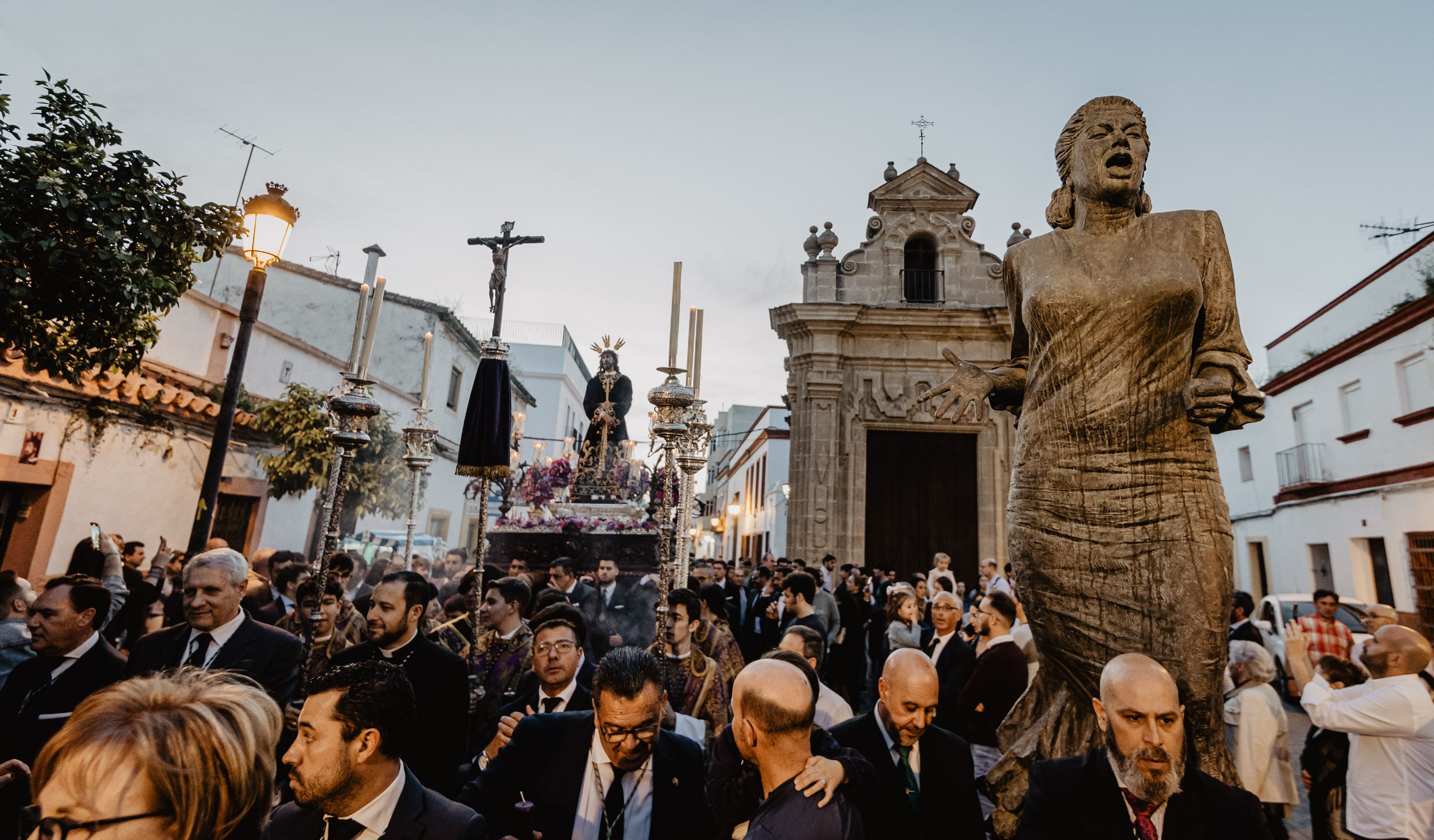El Señor de la Sentencia passando junto al monumento a La Paquera en las puertas de la capilla.