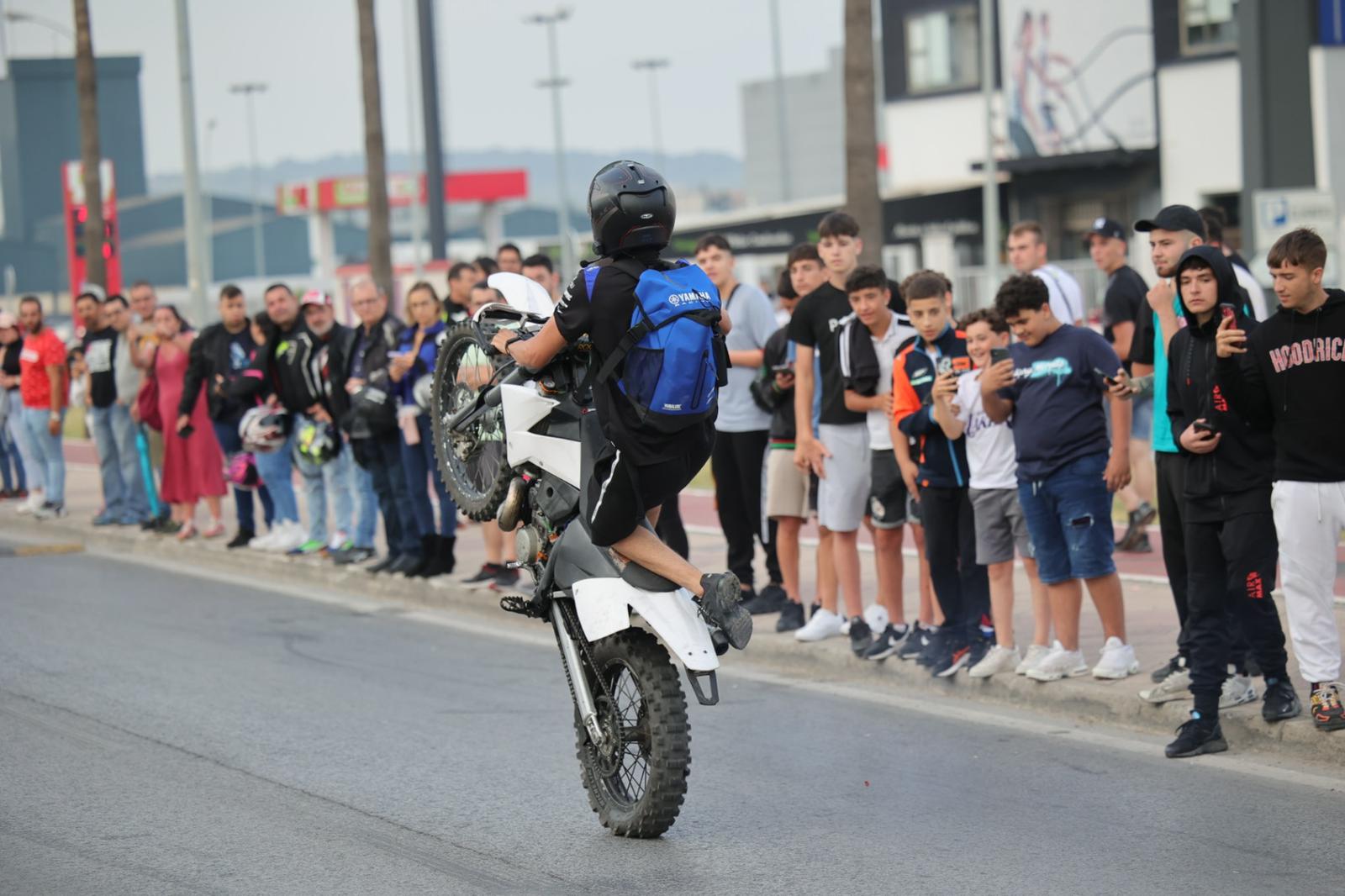 Jóvenes captando con sus móviles la acrobacia del motero.