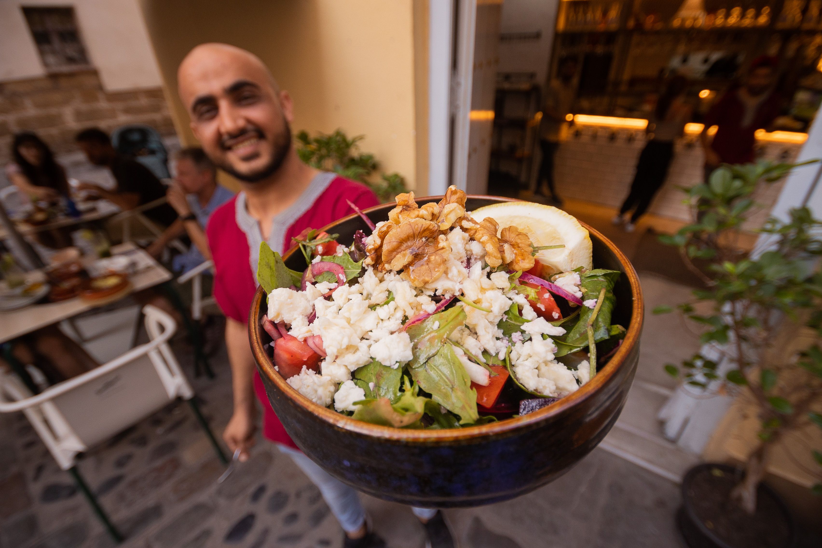 Wasim lleva una ensalada a la terraza del local. 