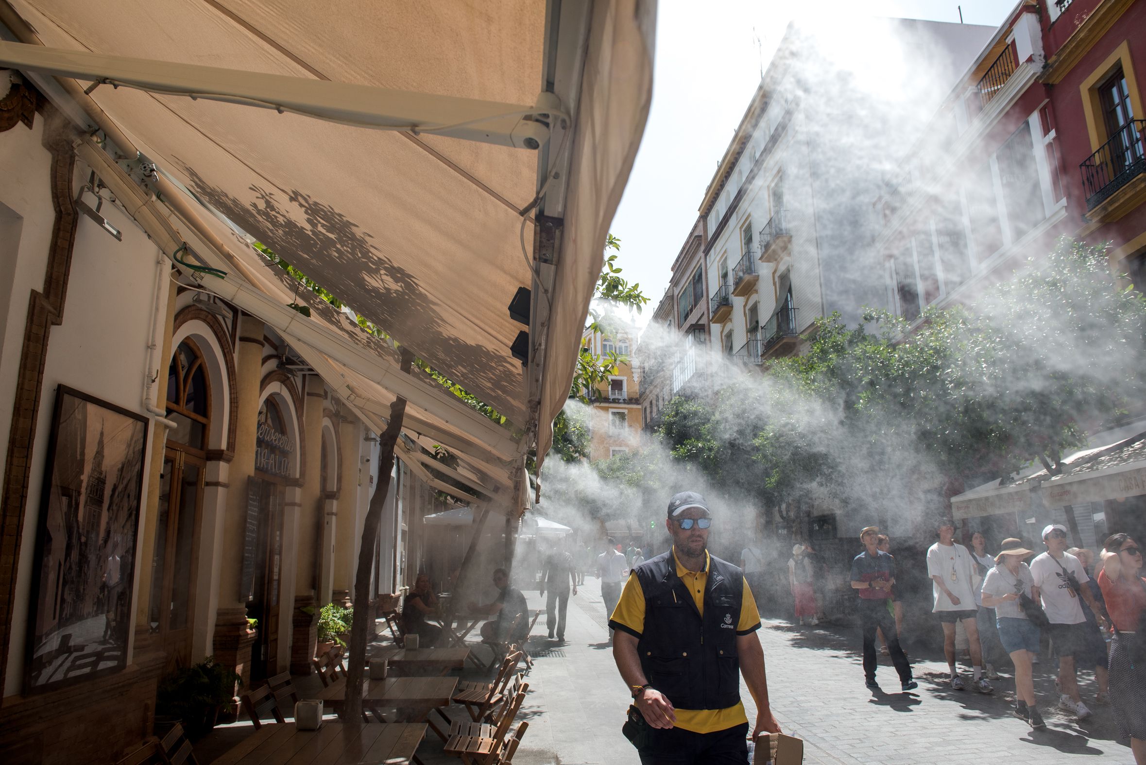 Varias personas, por el centro de Sevilla, durante una ola de calor en Andalucía.