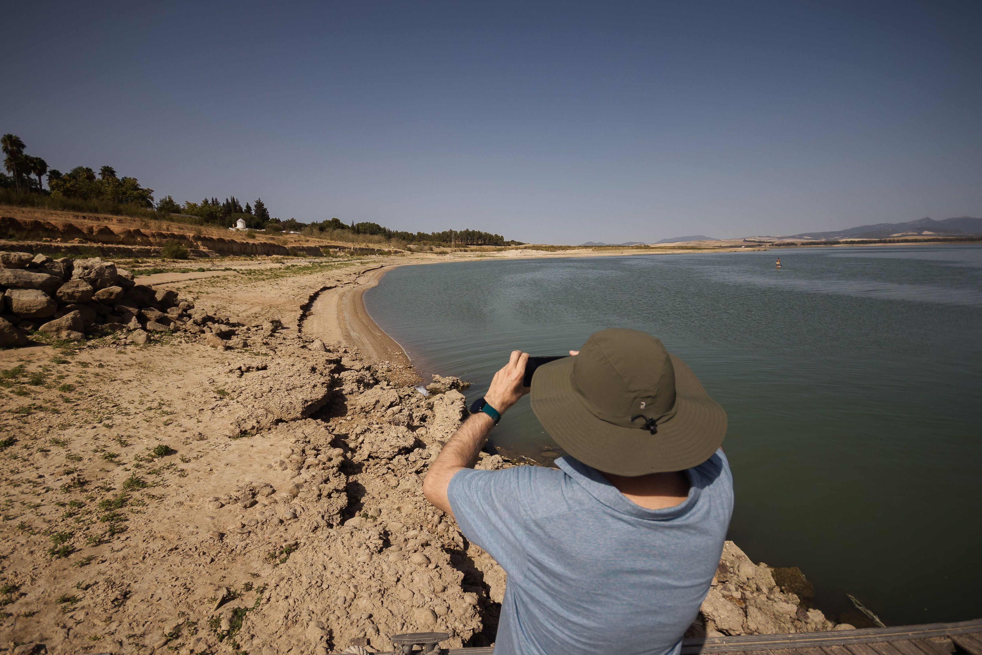 El embalse de Bornos donde una persona toma fotos de la bajada del agua, que se evidencia en la orilla.   MANU GARCÍA 