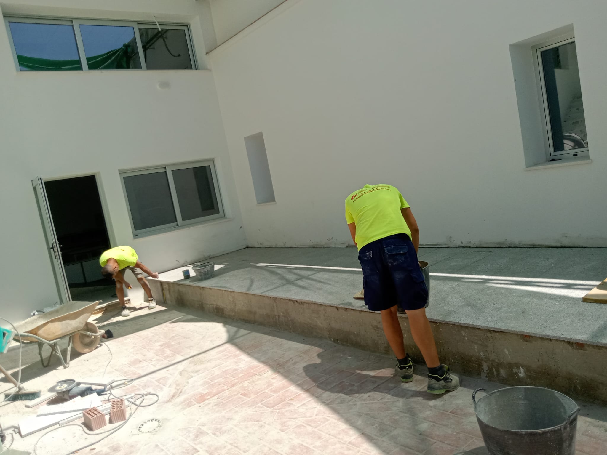 Dos operarios trabajan en el escenario sobre el que se ubicará la pantalla en Puerto Serrano.