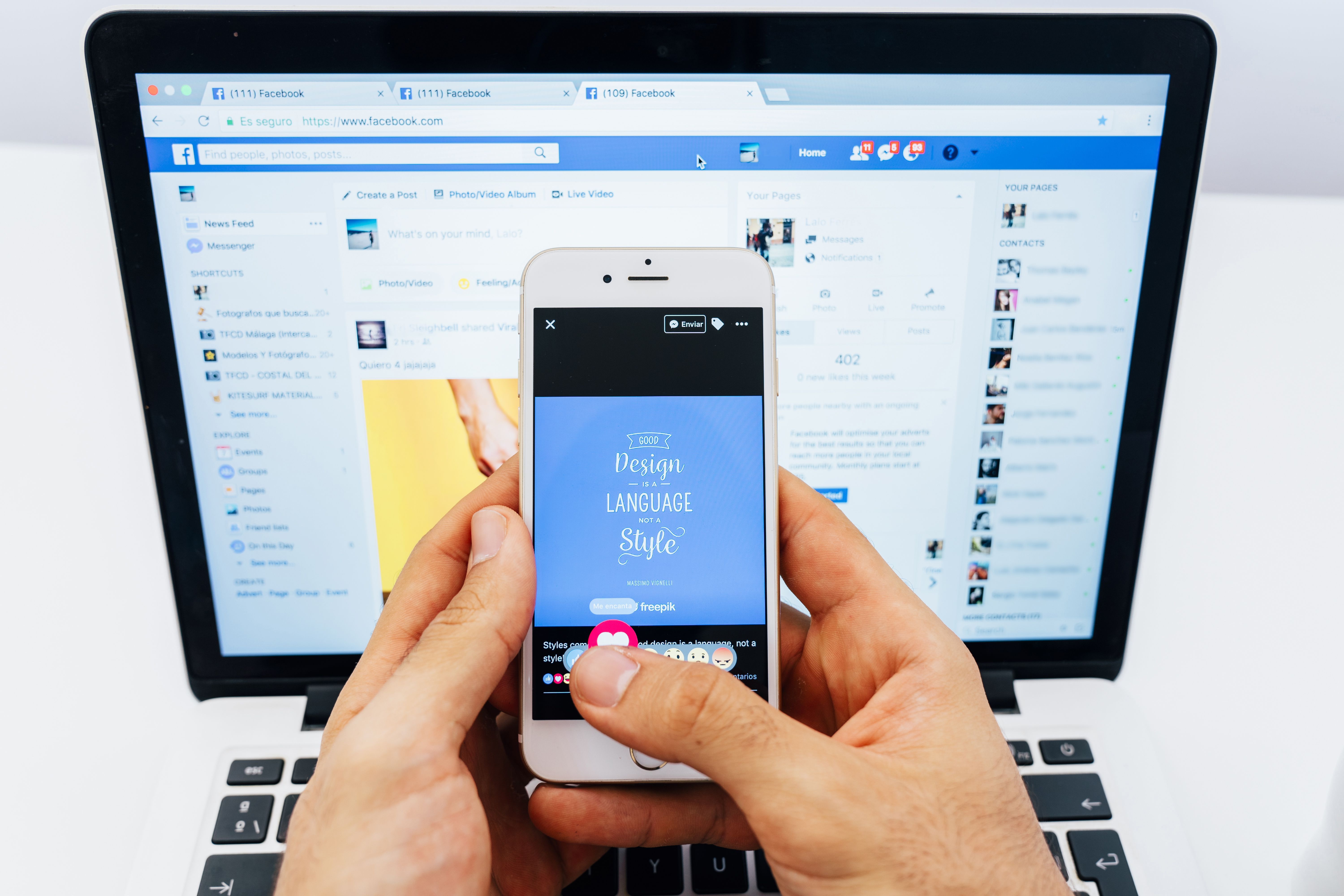 Una persona usa un móvil con Facebook al fondo.
