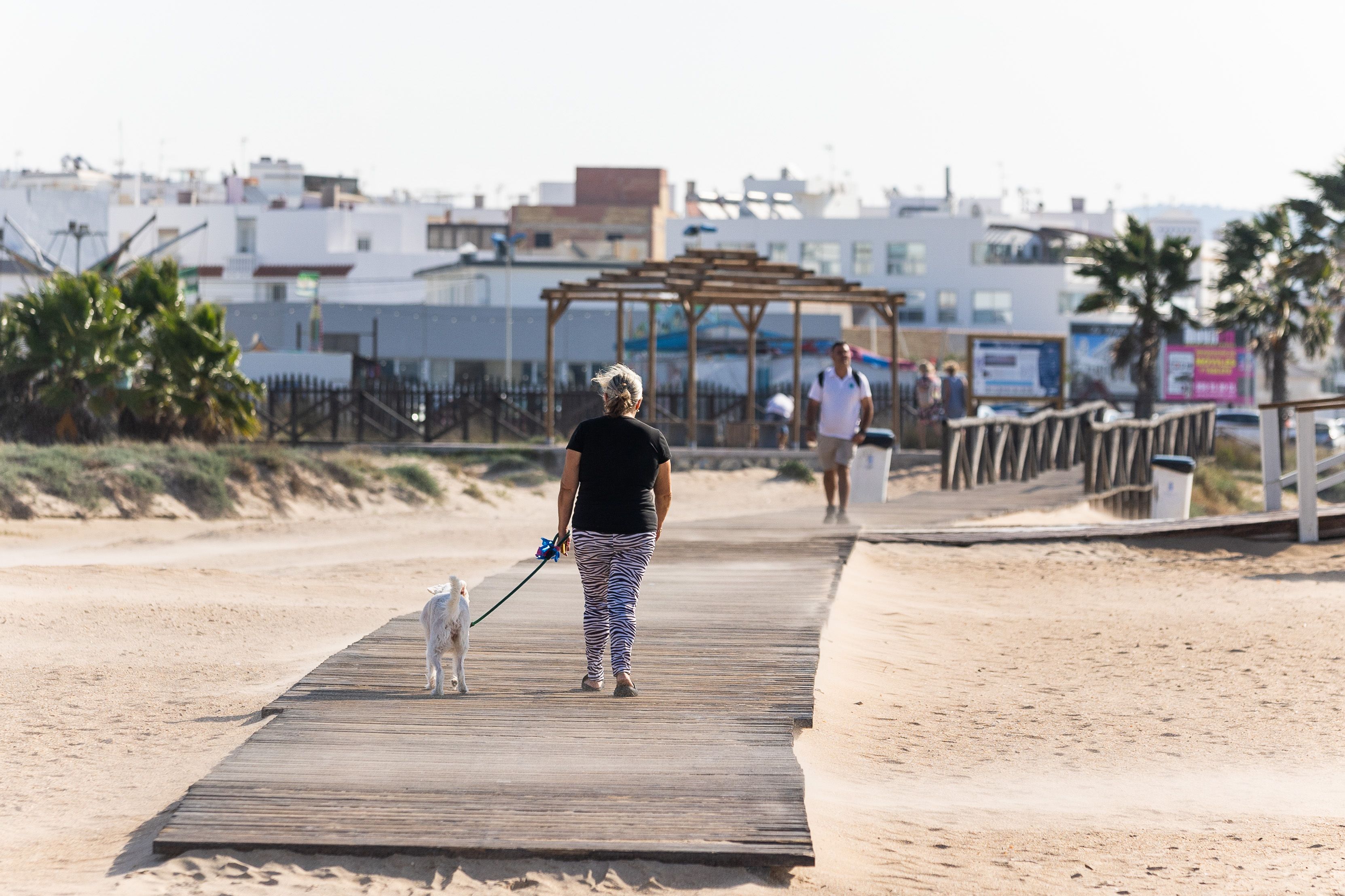 Vecinos y turistas en una de las pasarelas de acceso a la playa de Los Bateles.