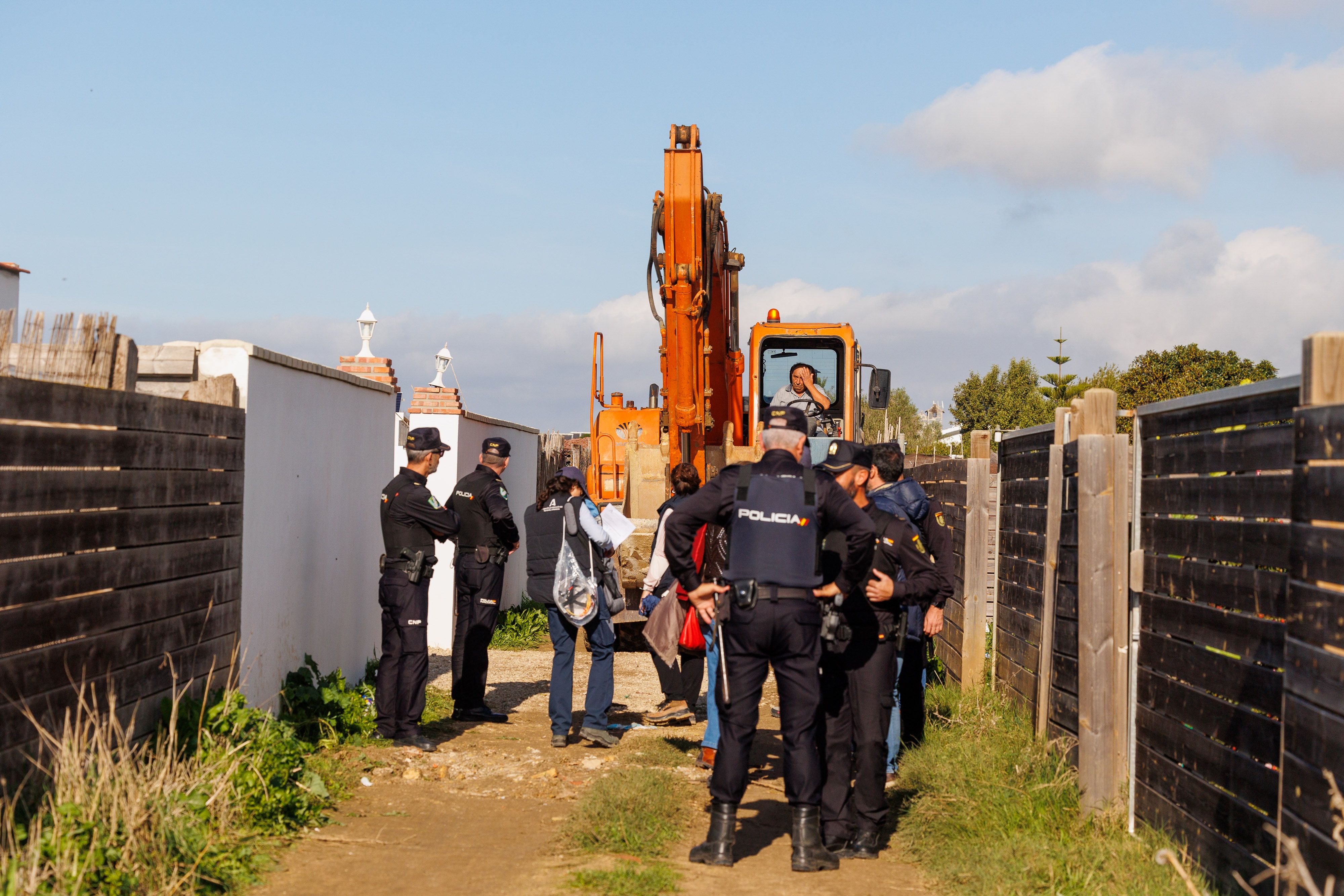 Funcionarios, policías y guardias civiles, junto a la excavadora averiada, este martes, en el primero de los muchos derribos que se esperan en El Palmar.