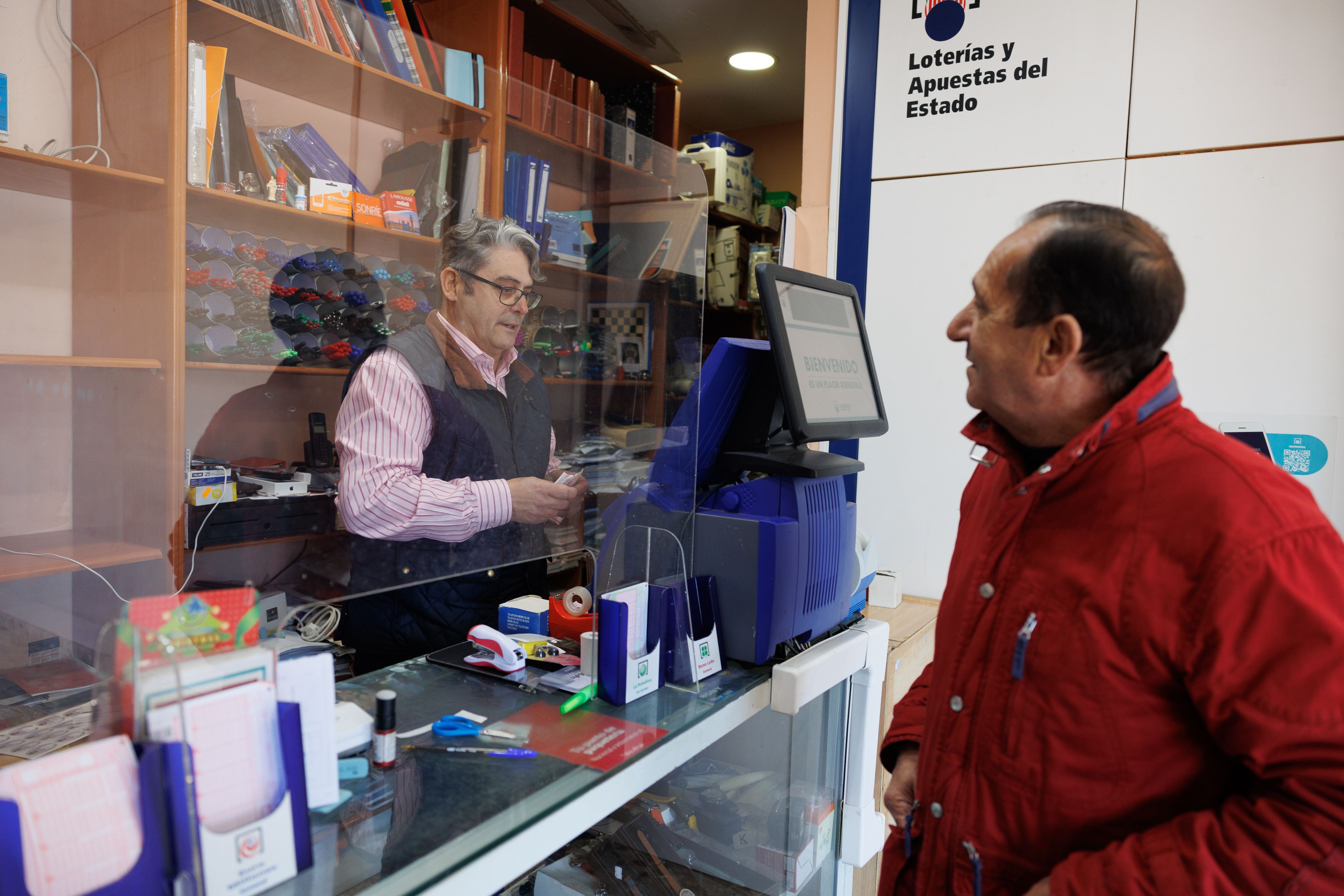 Biedma en el interior del negocio ante la máquina expendedora de apuestas. 