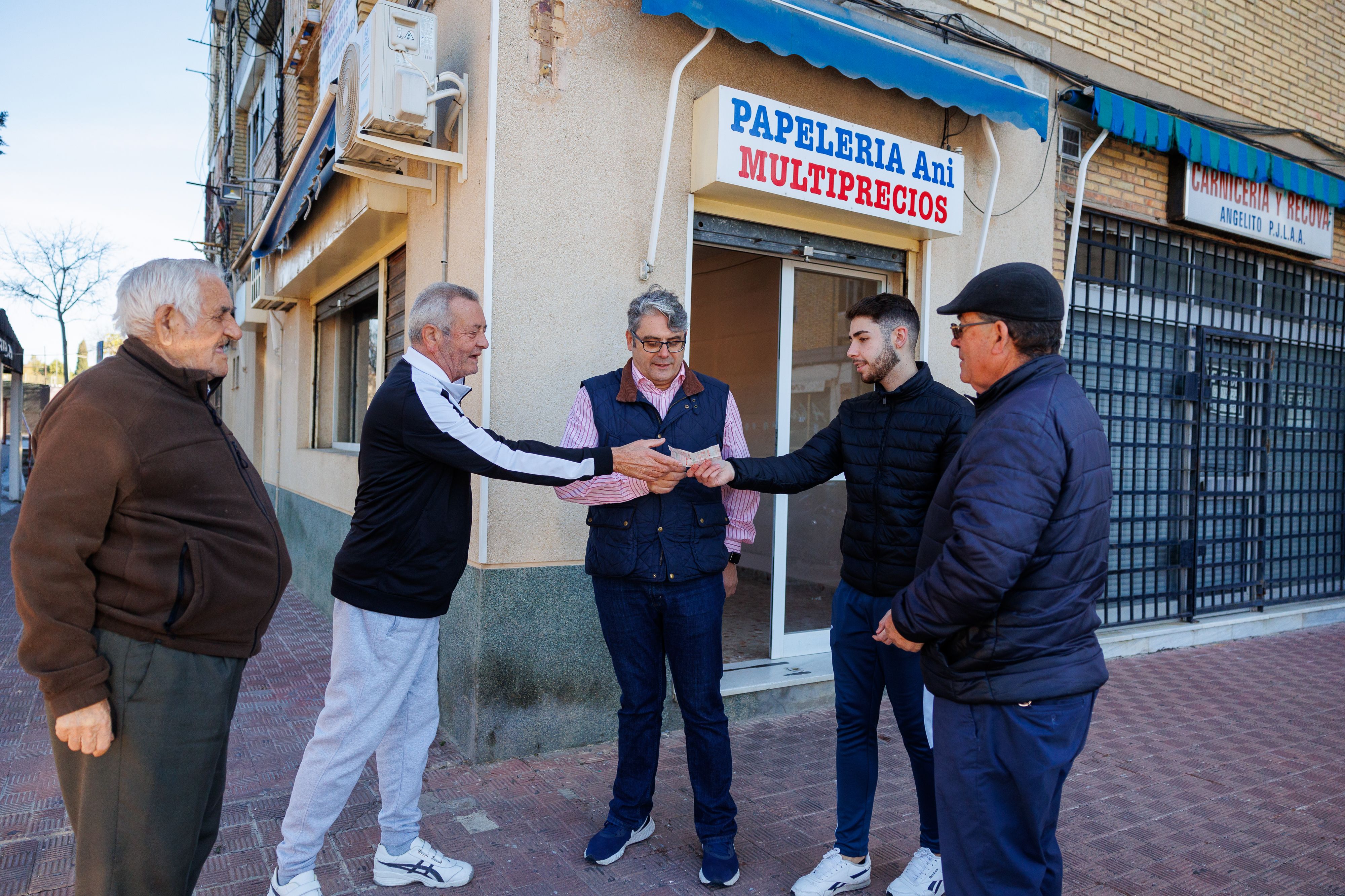Amigos y vecinos reunidos en la puerta de la papelería. 