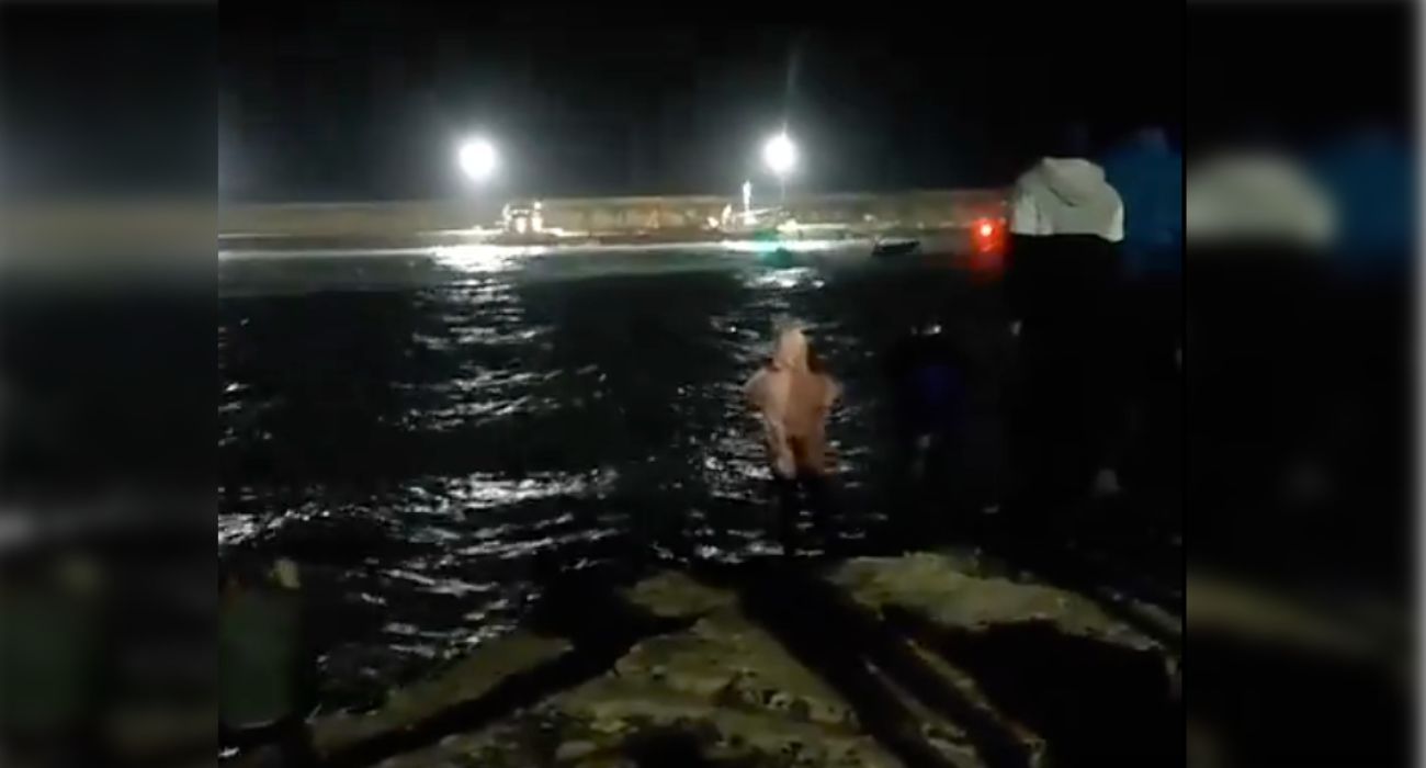 Varias personas, desde la orilla, jalean las embestidas de los narcos contra la patrullera de la Guardia Civil.