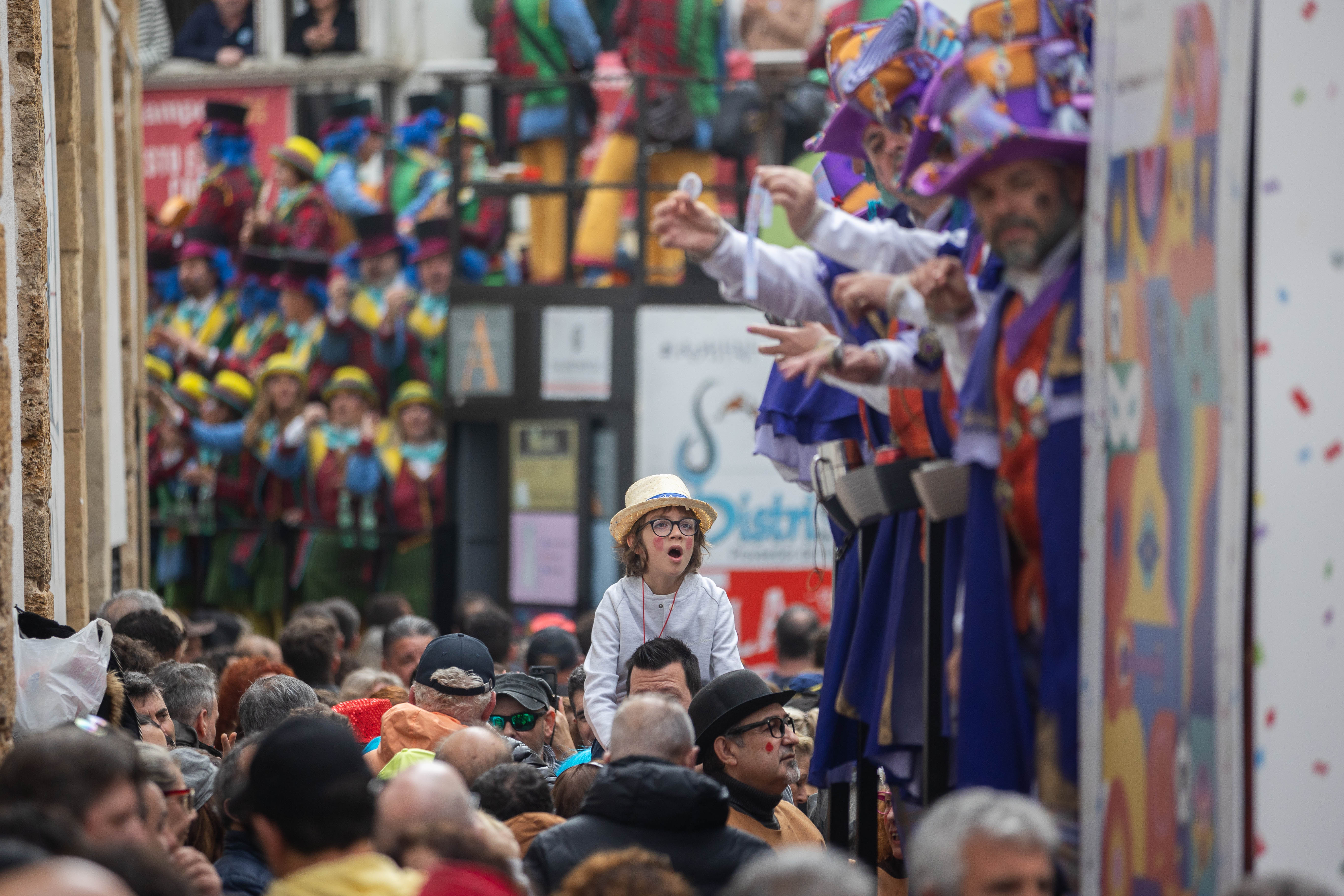 Un niño, a hombros, oye a un coro en la calle Libertad, junto al Mercado Central, este lunes festivo local.
