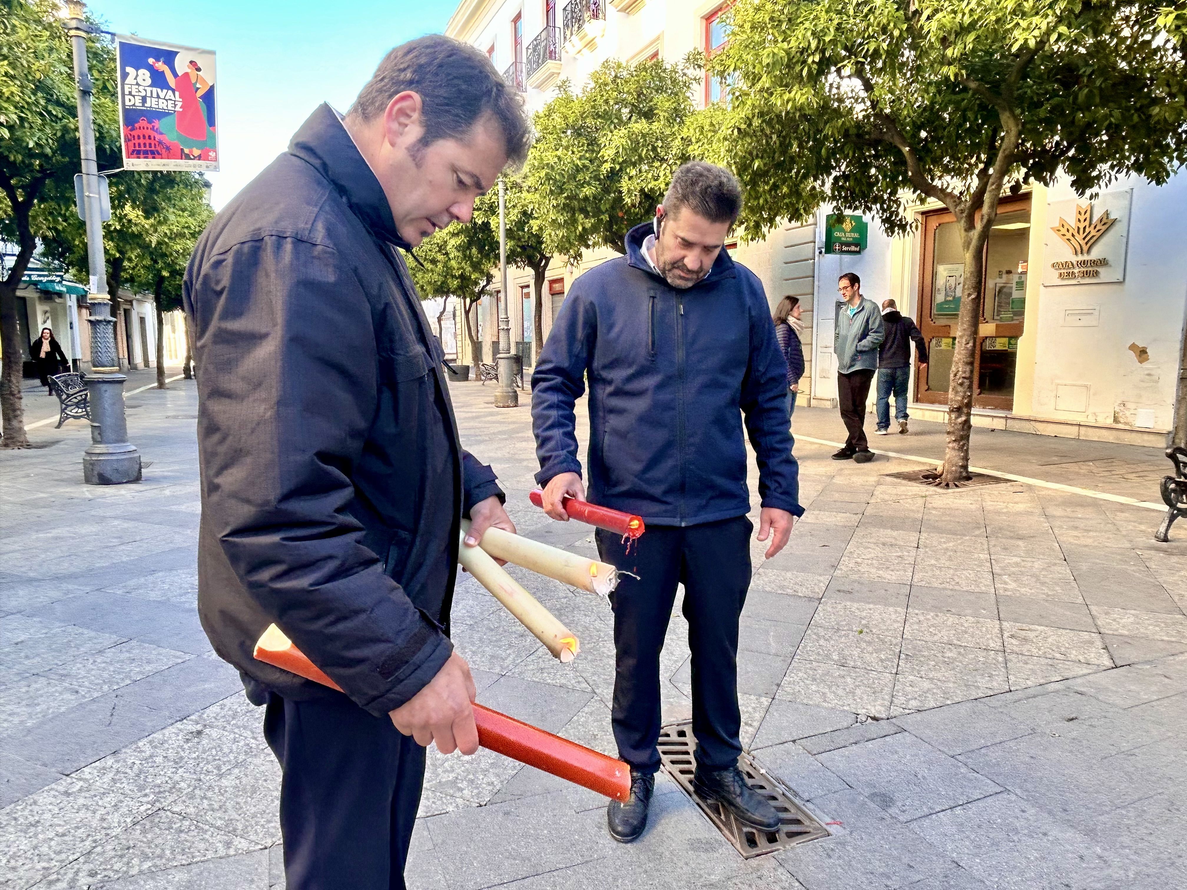 Los dos operarios en la calle Larga esparciendo cera en el pavimento.
