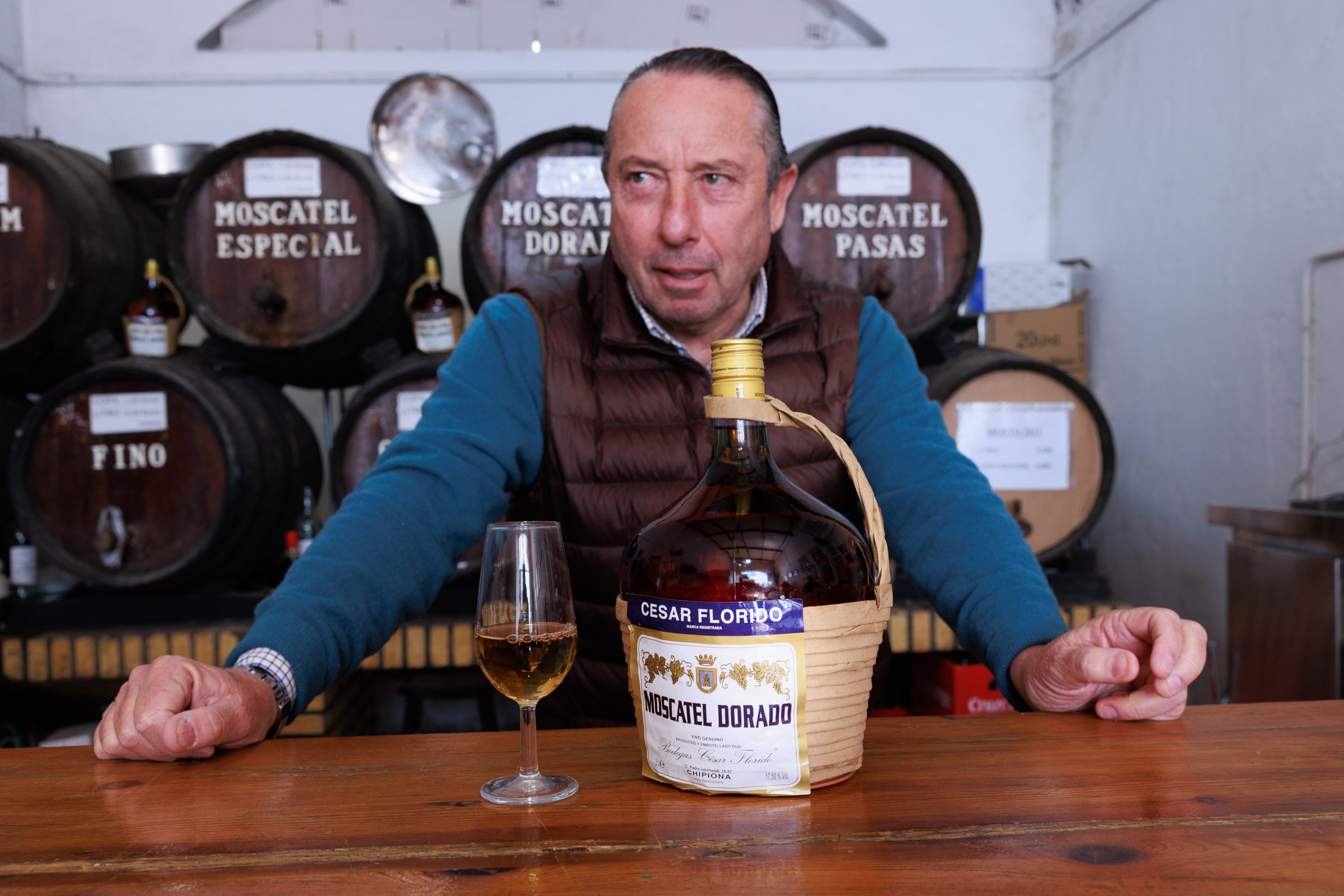 César Florido en la barra del despacho de vinos de su bodega, junto a una damajuana de moscatel dorado.