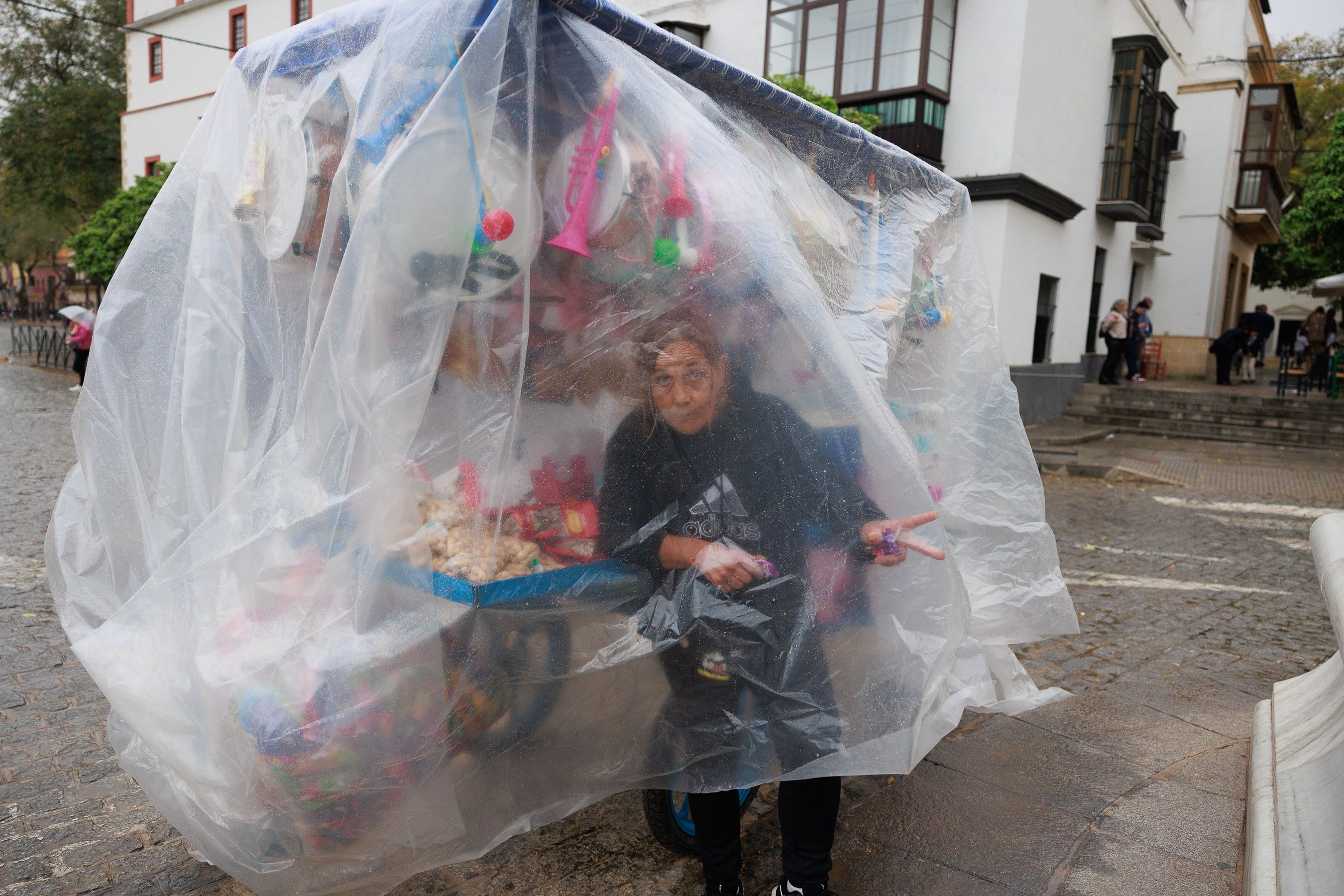 Carmen intenta cubrirse, junto a su carro, de la lluvia, que apenas ha dado tregua esta Semana Santa.