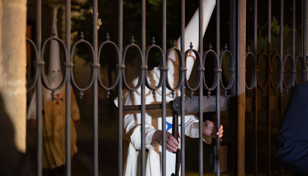 Un nazareno de Humildad y Paciencia cerrando la reja de la Trinidad. 
