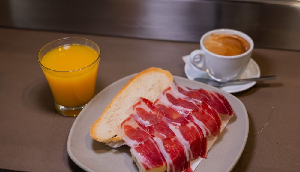 Detalle de la tostada con jamón, café y zumo de naranja natural.
