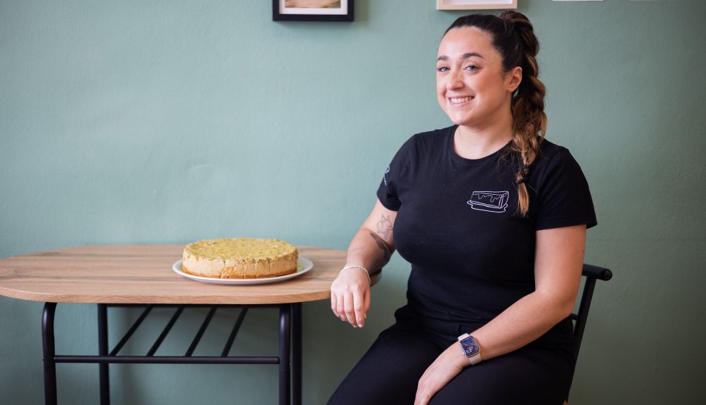 Marian, hija de Marian y Juanma, junto a una tarta de queso de pistacho.