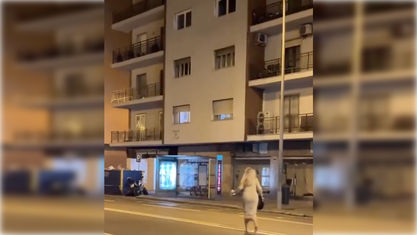 Momento en el que la joven va a recoger las chanclas que le regalan desde un balcón. Momento en el que la joven va a recoger las chanclas que le regalan desde un balcón.