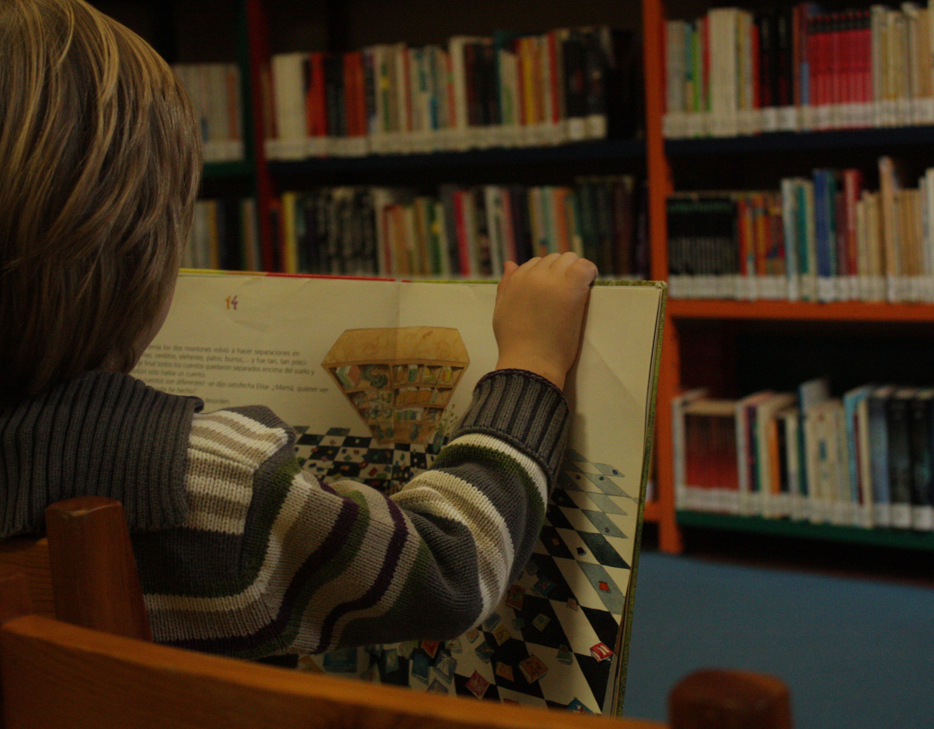 Un niño lee en una biblioteca.