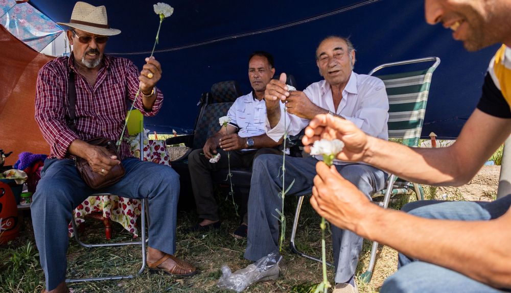 Los hombres preparan los claveles en la explanada.