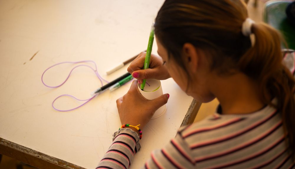 Una niña coloreando su vaso de cartón durante el taller.