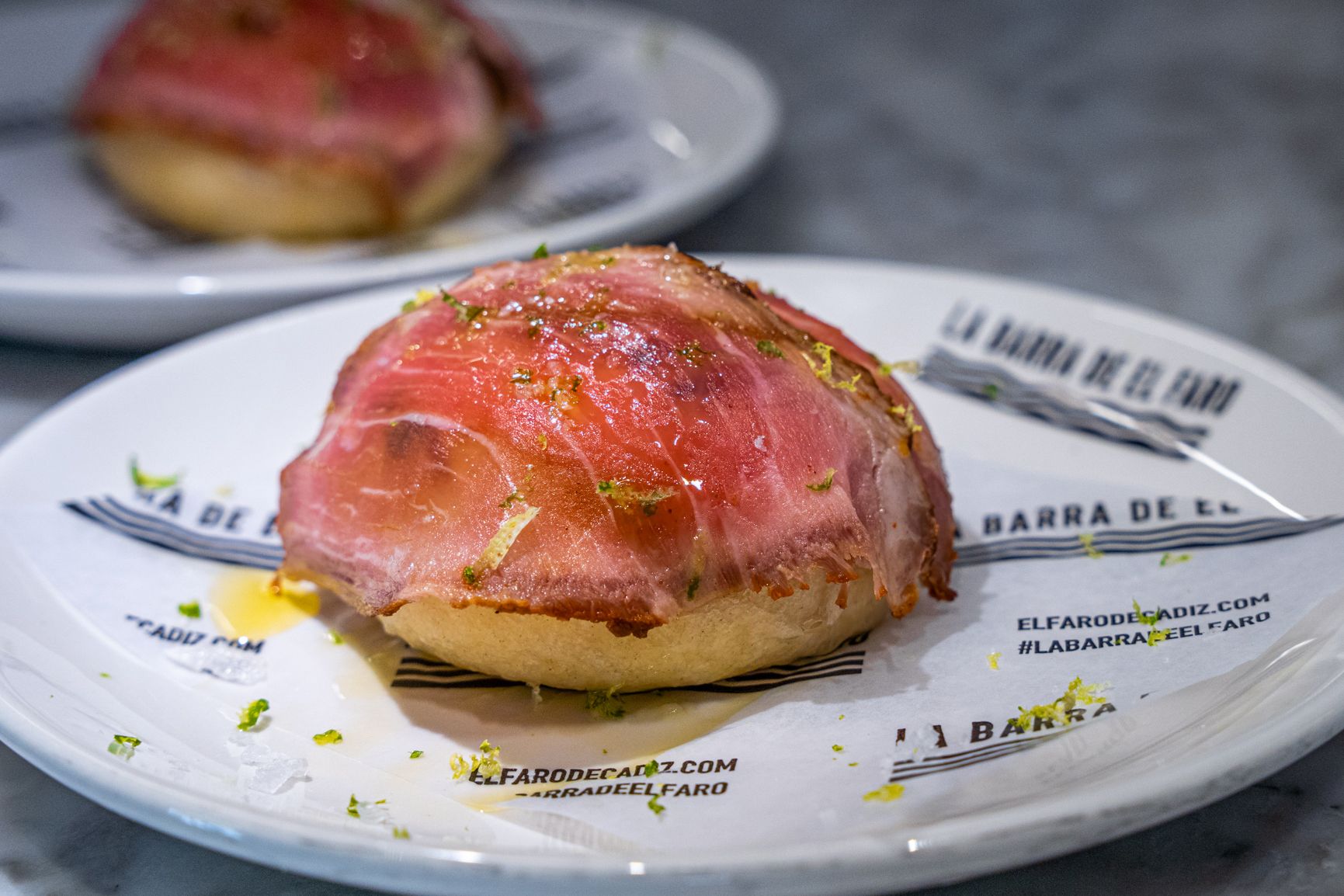 Mollete de presa en un plato que muestra la nueva imagen corporativa, propia, de la barra.  REYNA