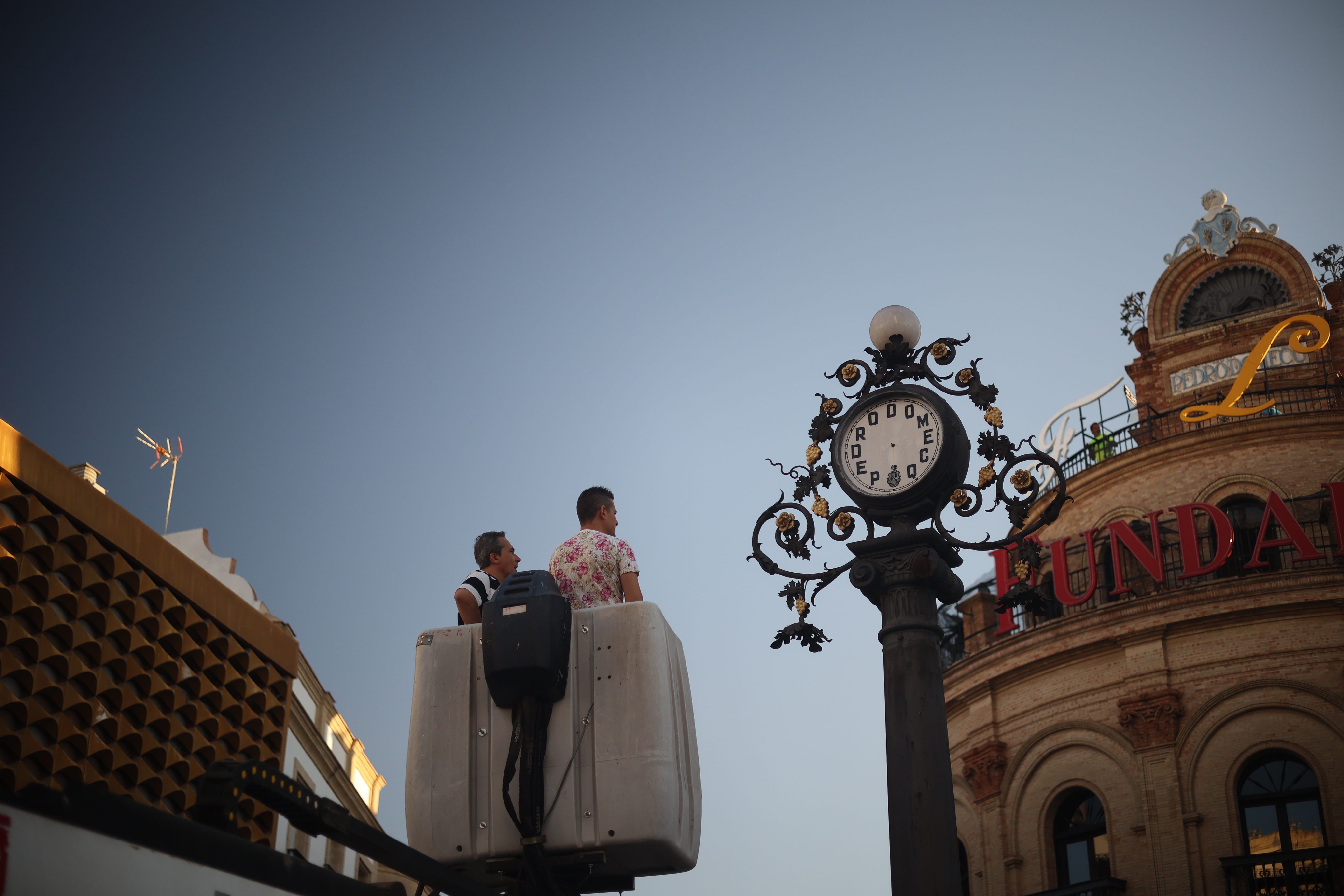 Los operarios, frente al reloj de Domecq en el Gallo Azul, antes de ser desmontado.