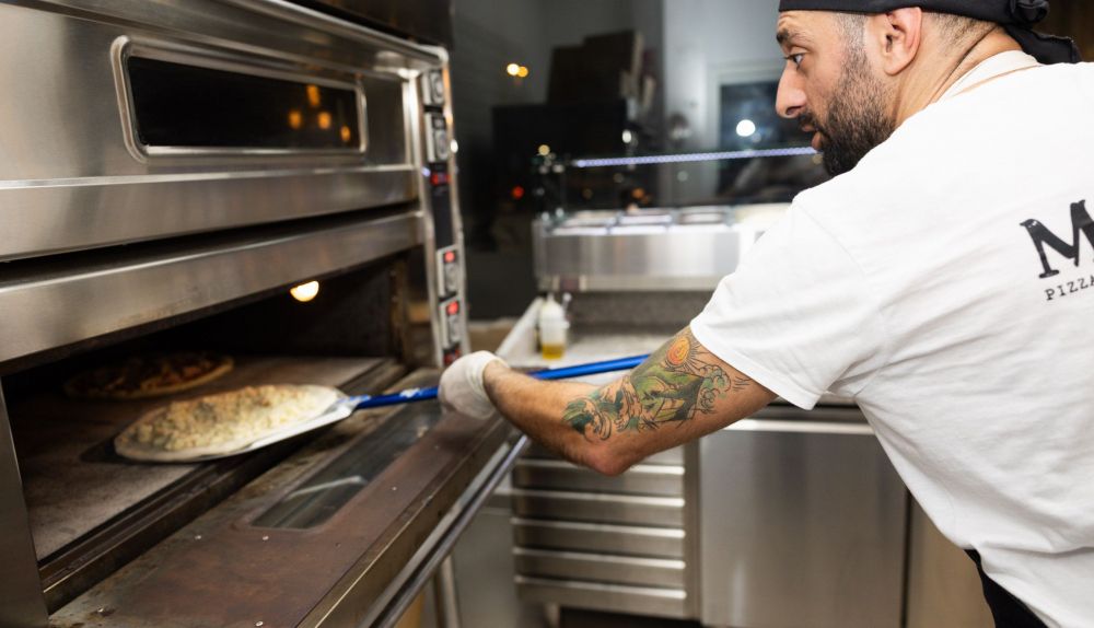 Angelo mete una de las pizzas al horno.