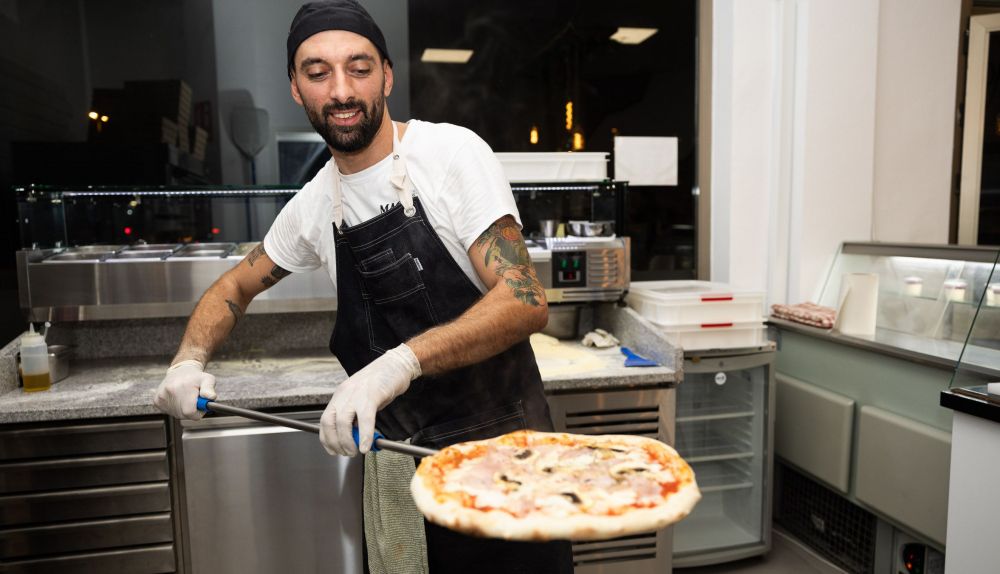 Angelo saca una de sus pizzas del horno.